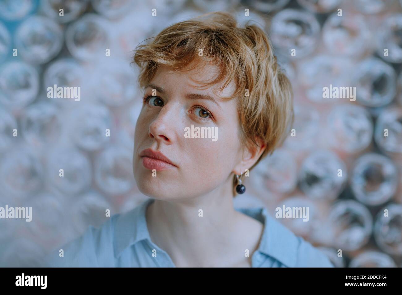 Une artiste féminine attentive contre la peinture enveloppée dans un film à bulles Banque D'Images