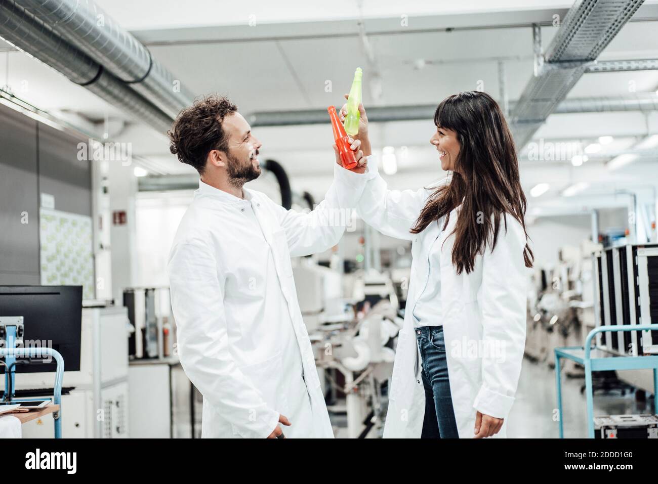 Des techniciens hommes et femmes qui toaster les boissons en se tenant debout sont heureux laboratoire Banque D'Images