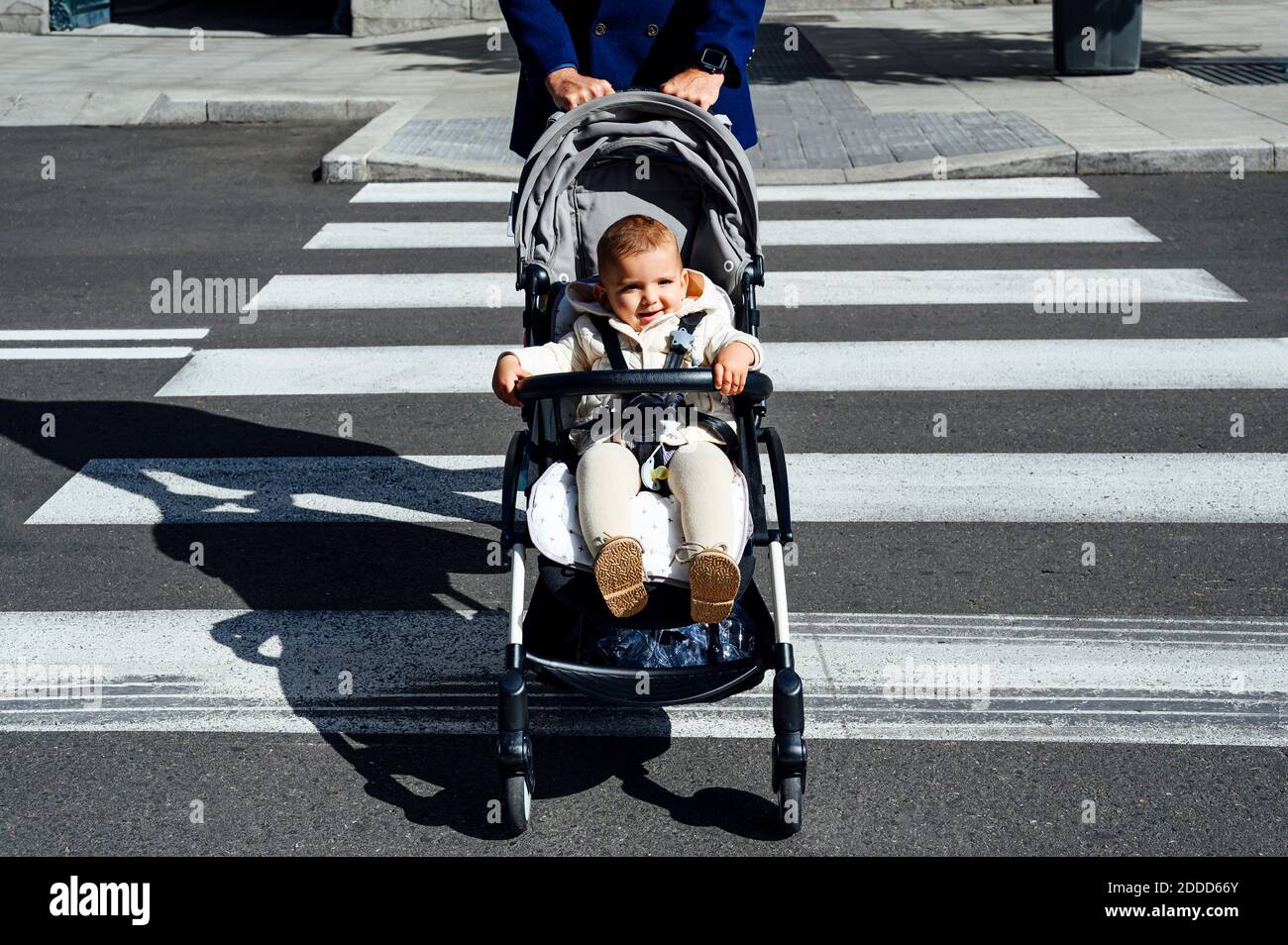 Père avec bébé souriant dans poussette de bébé traversant la route à l'intérieur ville Banque D'Images