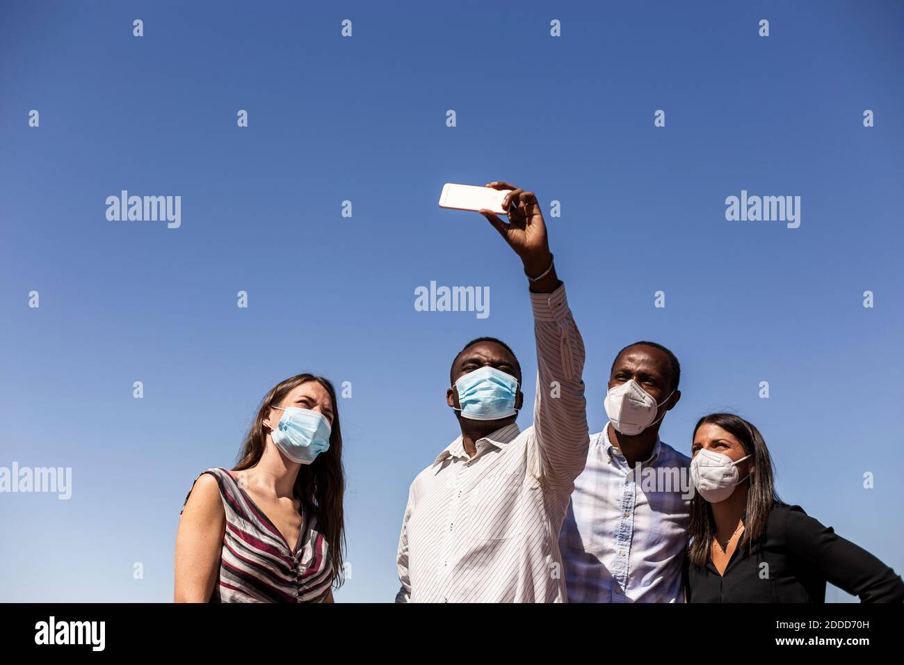 Professionnels d'affaires prenant selfie avec des masques de protection contre les clairs ciel bleu le jour ensoleillé Banque D'Images