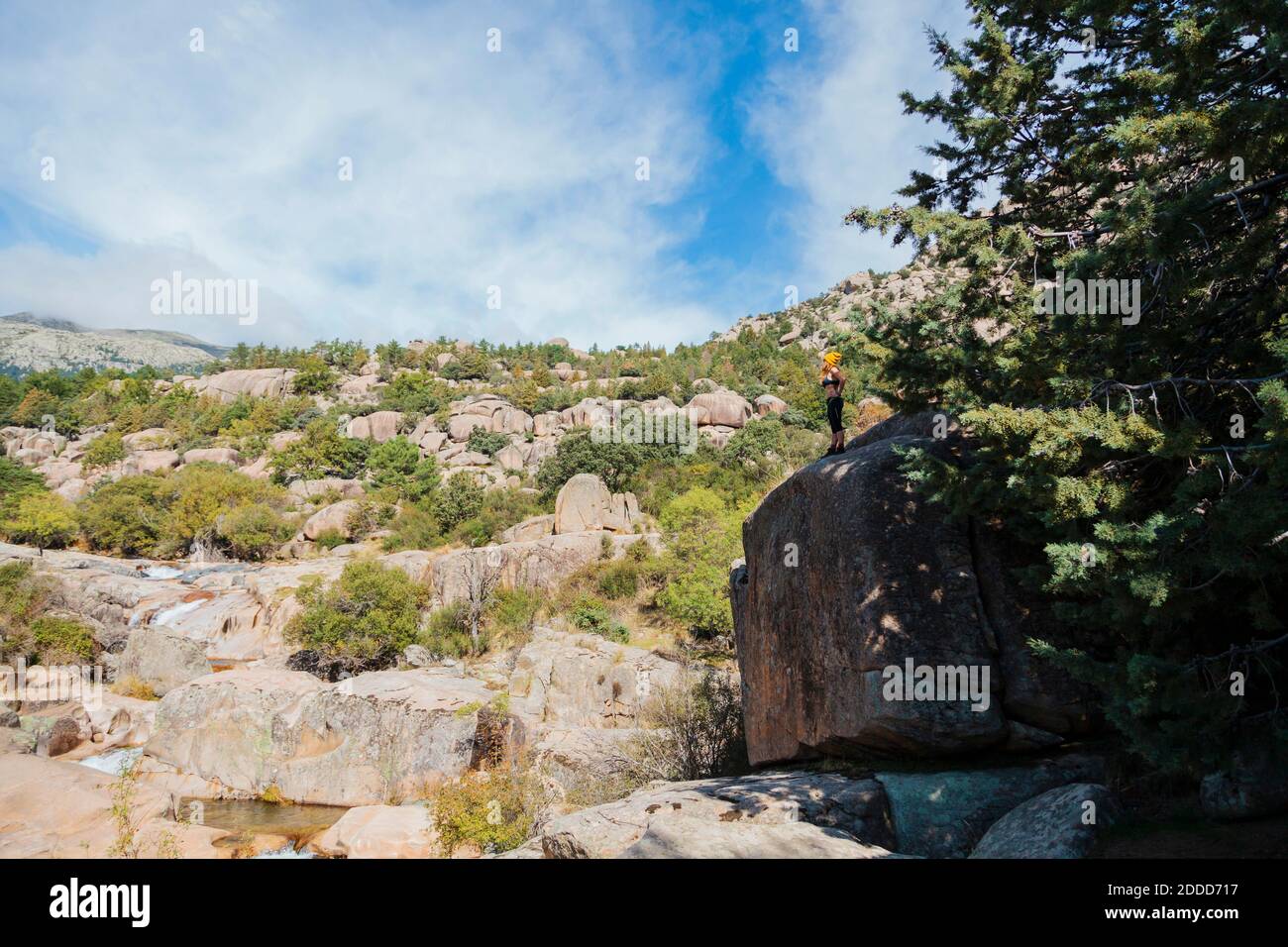 Femme trekker admirant la vue tout en se tenant sur un grand rocher dans la forêt à la Pedriza, Madrid, Espagne Banque D'Images