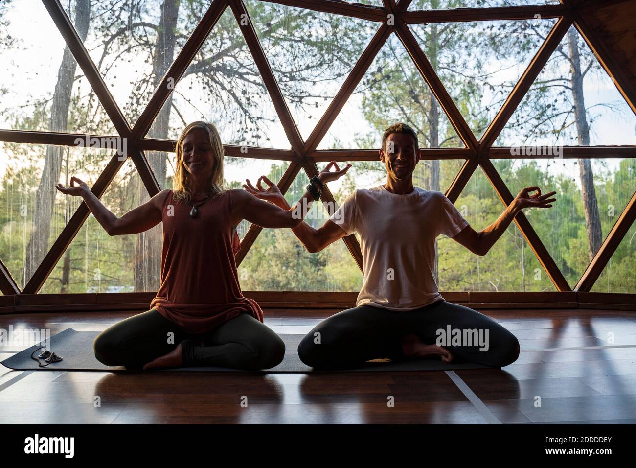 Femme souriante et homme pratiquant le yoga contre la fenêtre en santé spa Banque D'Images