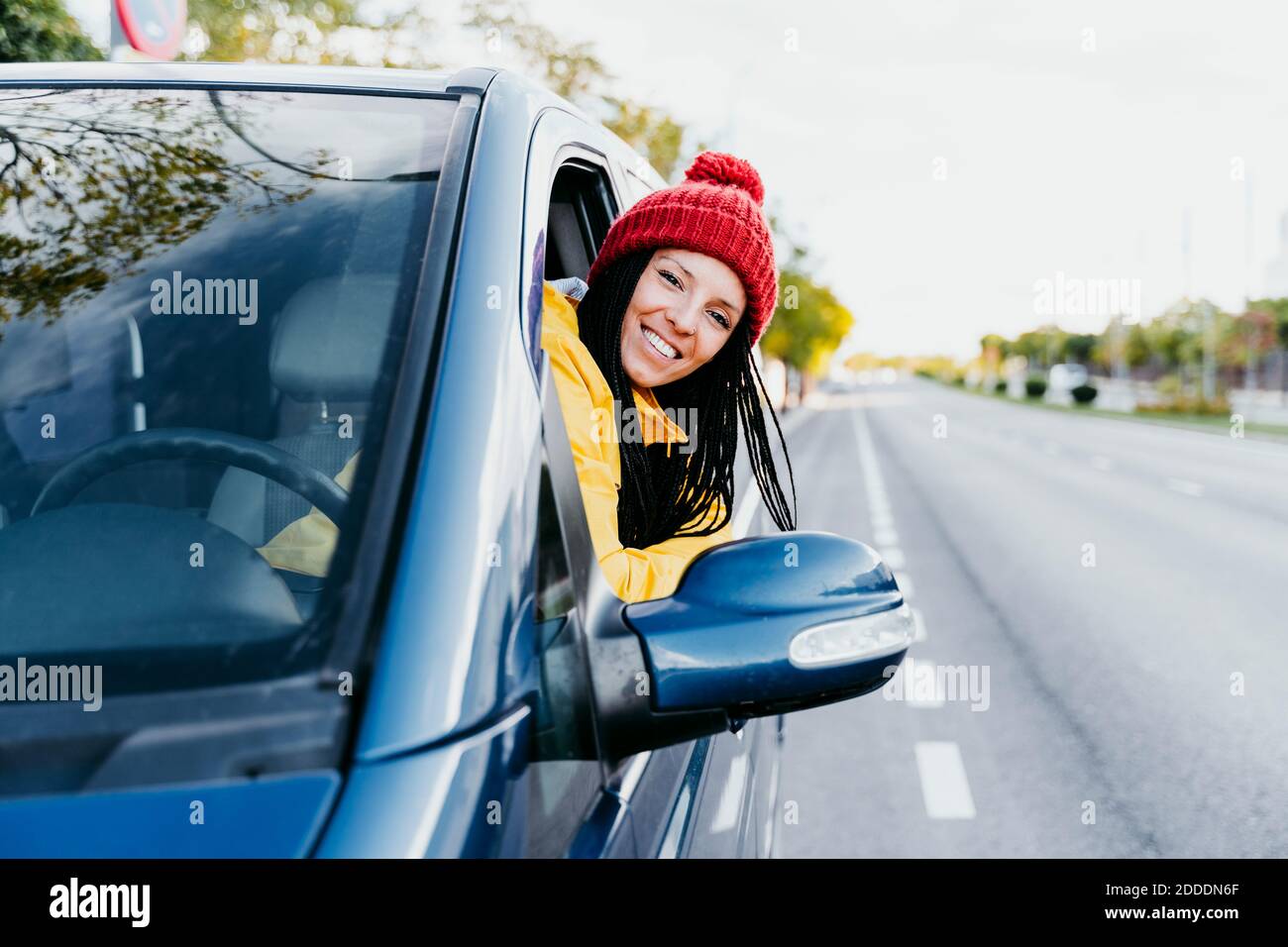 Femme souriante se penchée sur la fenêtre de la voiture pendant le voyage Banque D'Images