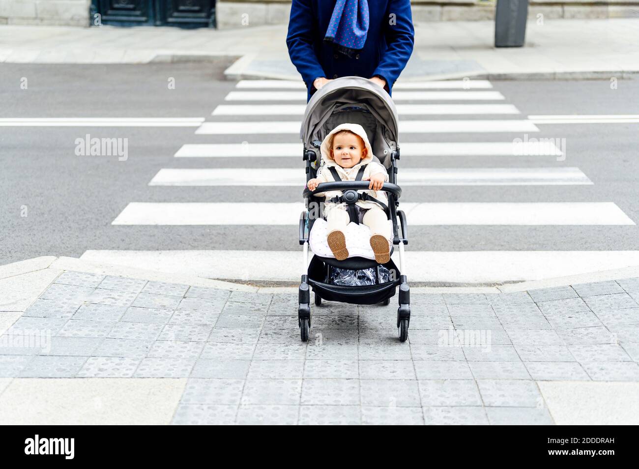 Homme traversant la route avec bébé garçon assis dans la poussette de bébé en ville Banque D'Images