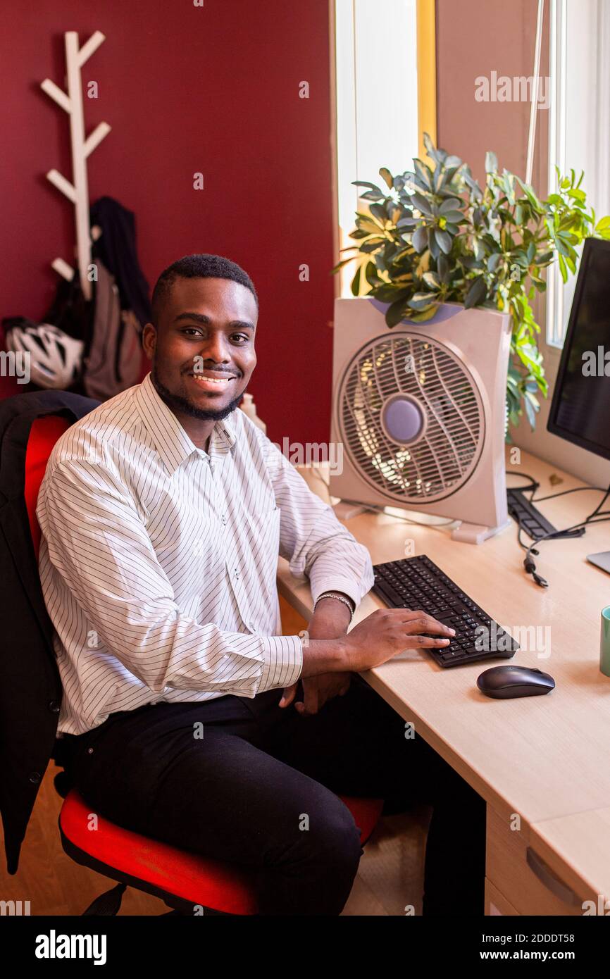 Jeune homme d'affaires souriant utilisant un ordinateur au bureau Banque D'Images