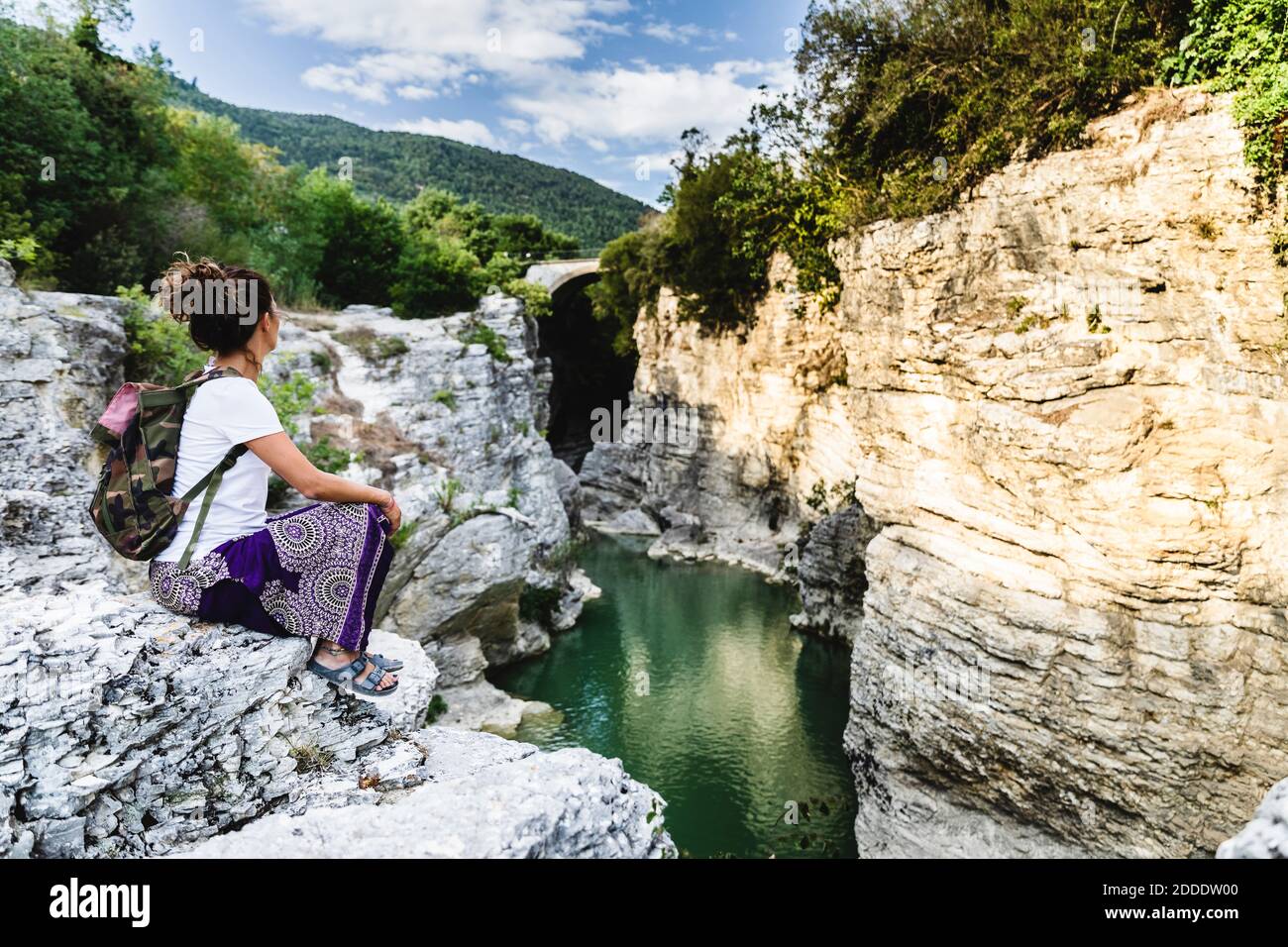 Femme regardant la vue sur la vallée tout en étant assise sur le rocher de la montagne à Marmitte Dei Giganti, Marche, Italie Banque D'Images