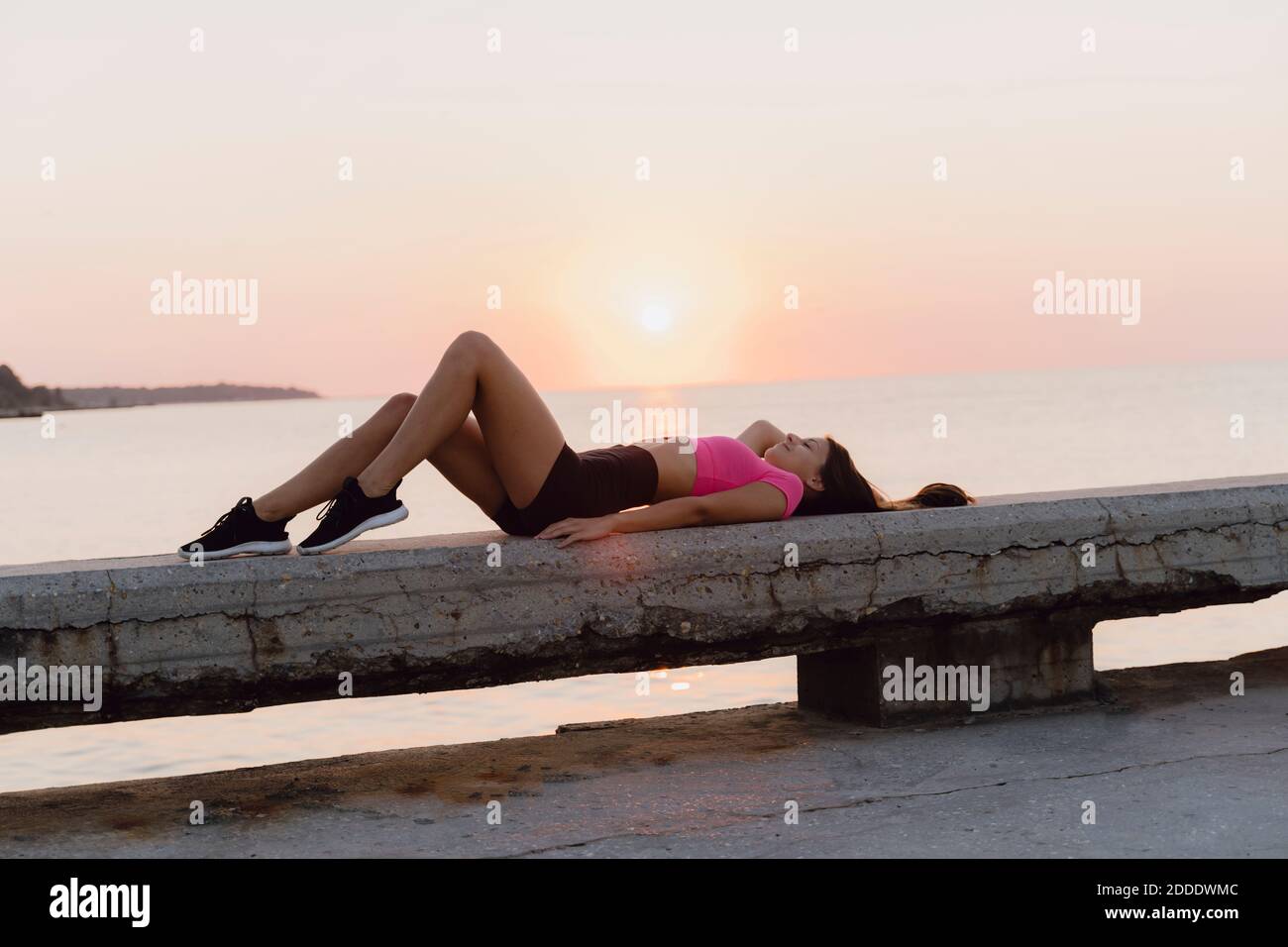 Femme se détendant sur le mur de retenue contre la mer Banque D'Images