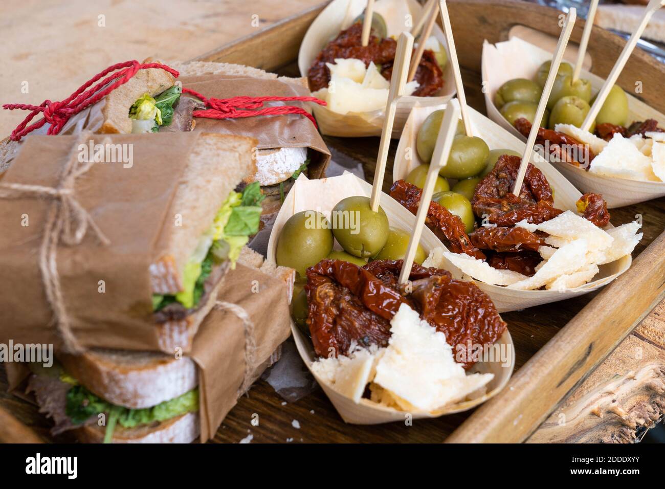 Sandwichs à la viande et aux légumes et paniers à tomates séchées, olives vertes et fromage sur un plateau en bois Banque D'Images