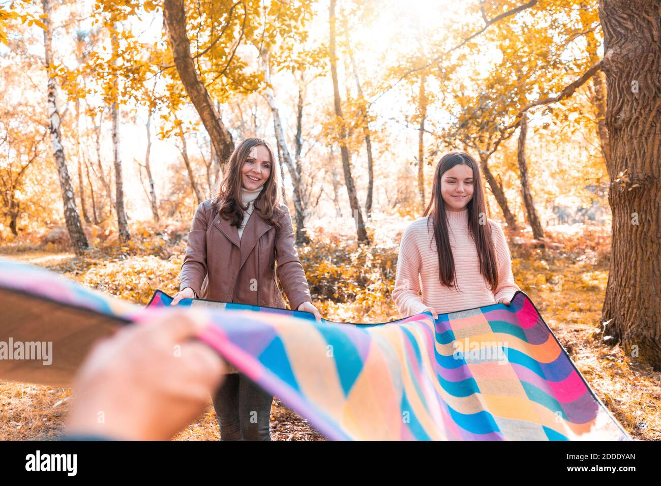 Une famille heureuse pose une couverture de pique-nique dans le parc en automne Banque D'Images