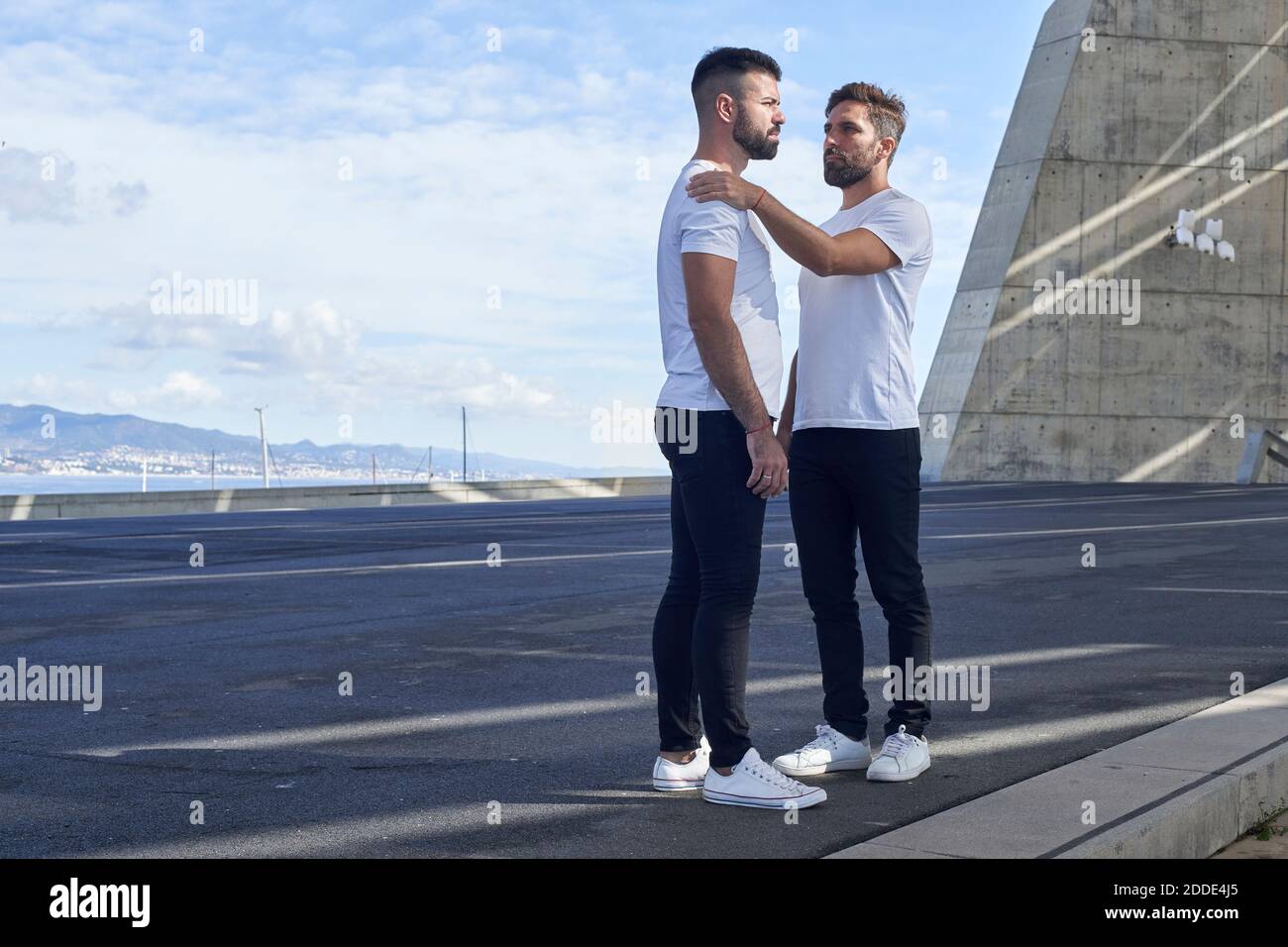 Couple gay debout au Parc del Forum contre le ciel, Barcelone, Espagne Banque D'Images