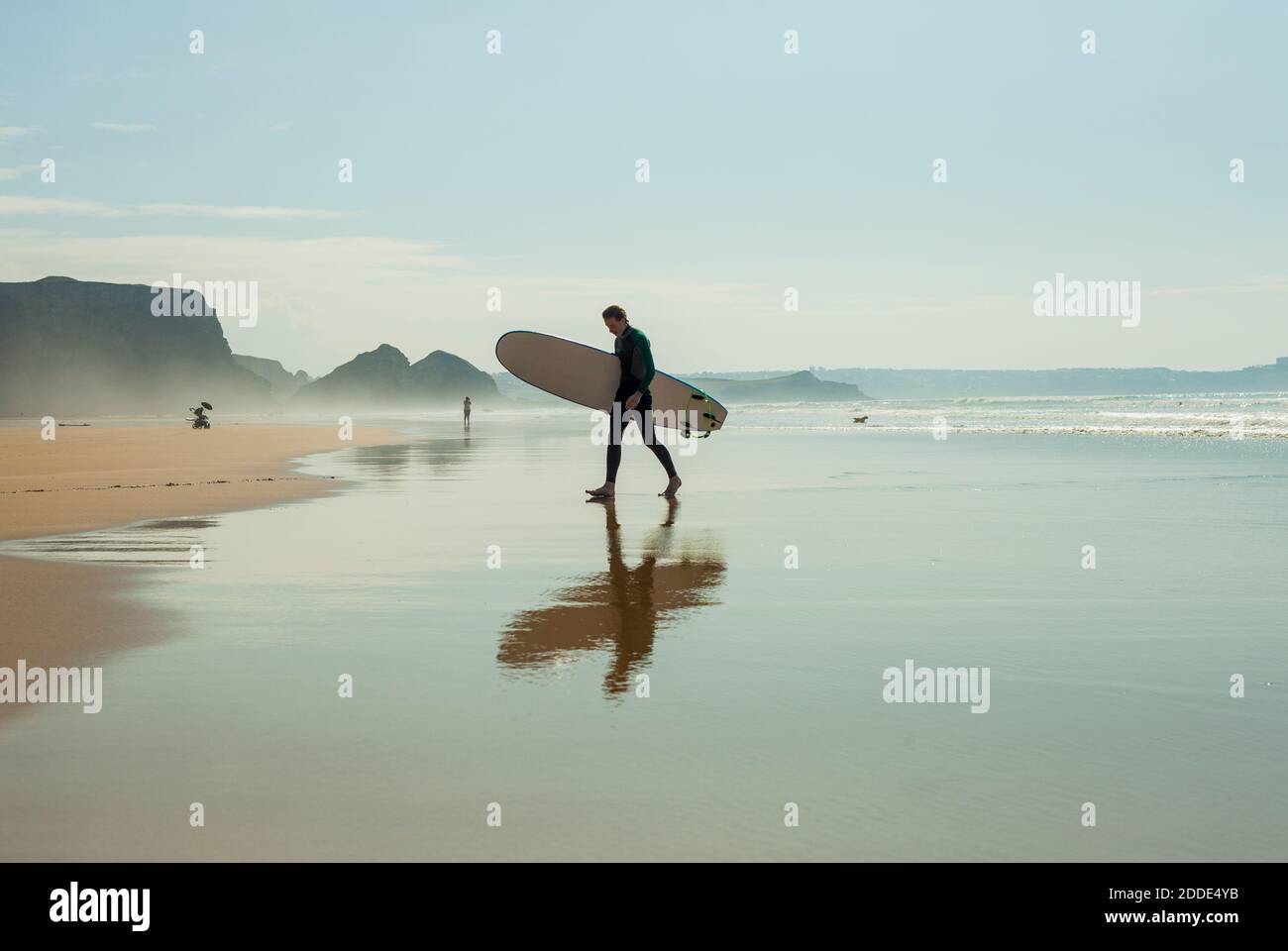 Réflexion d'un adolescent de marche avec planche de surf contre le ciel à plage sur la rive Banque D'Images