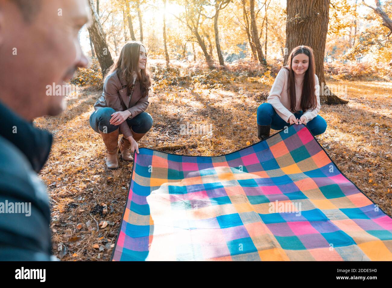 Famille posant une couverture de pique-nique dans le parc pendant l'automne Banque D'Images