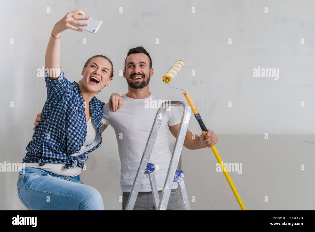 Une femme prend une photo au téléphone avec son petit ami. Ils tiennent un rouleau Banque D'Images