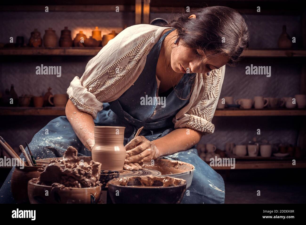 Maître d'artisan charmant travaillant sur la roue de potter avec de l'argile brute avec les mains. Fabrication artisanale. Banque D'Images