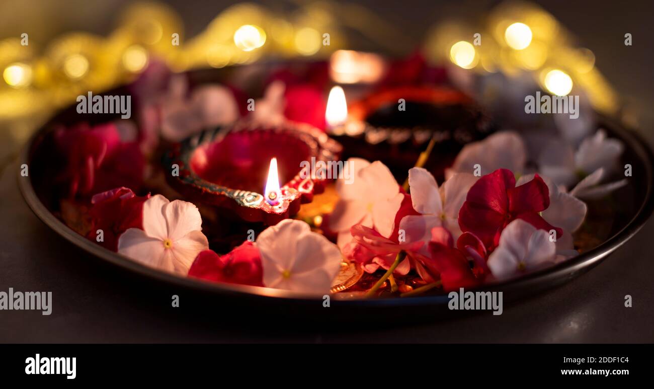 Lampes à huile Diwali colorées, lampes à huile Deepavali illuminées en belle formation avec des fleurs et des lumières en série sombres dans une formation de bokeh Banque D'Images