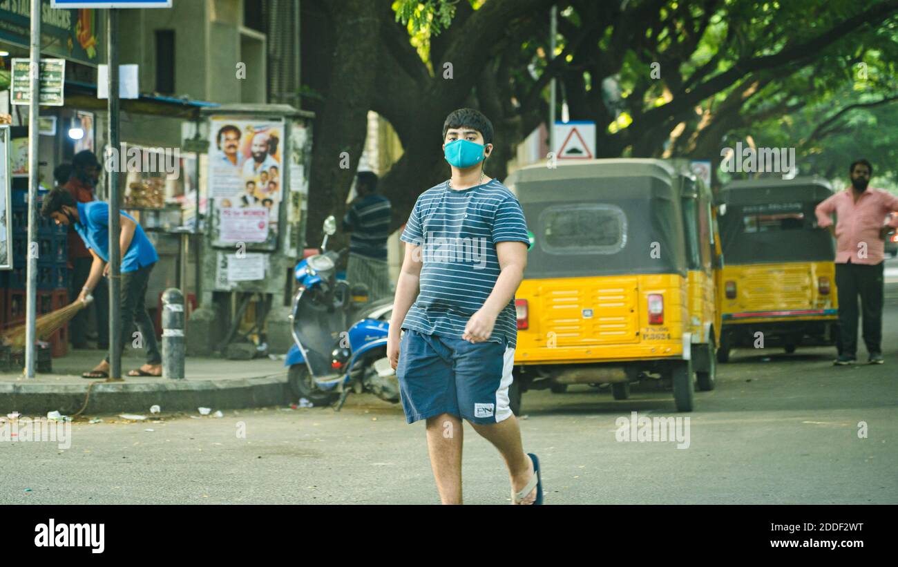 Un jeune adulte portant un masque facial et marchant dans une rue à Adyar. Banque D'Images