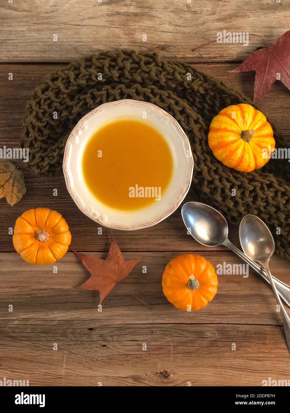 gros plan soupe de potiron sur une table en bois décorée de séchée feuilles d'automne Banque D'Images