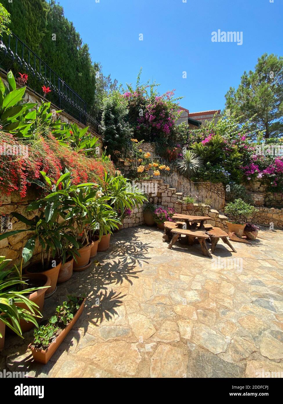 Jardin fleuri secret de villa de vacances d'été privée. Plantes et fleurs colorées avec un bureau esthétique en bois sur la terrasse de la maison d'été. Banque D'Images