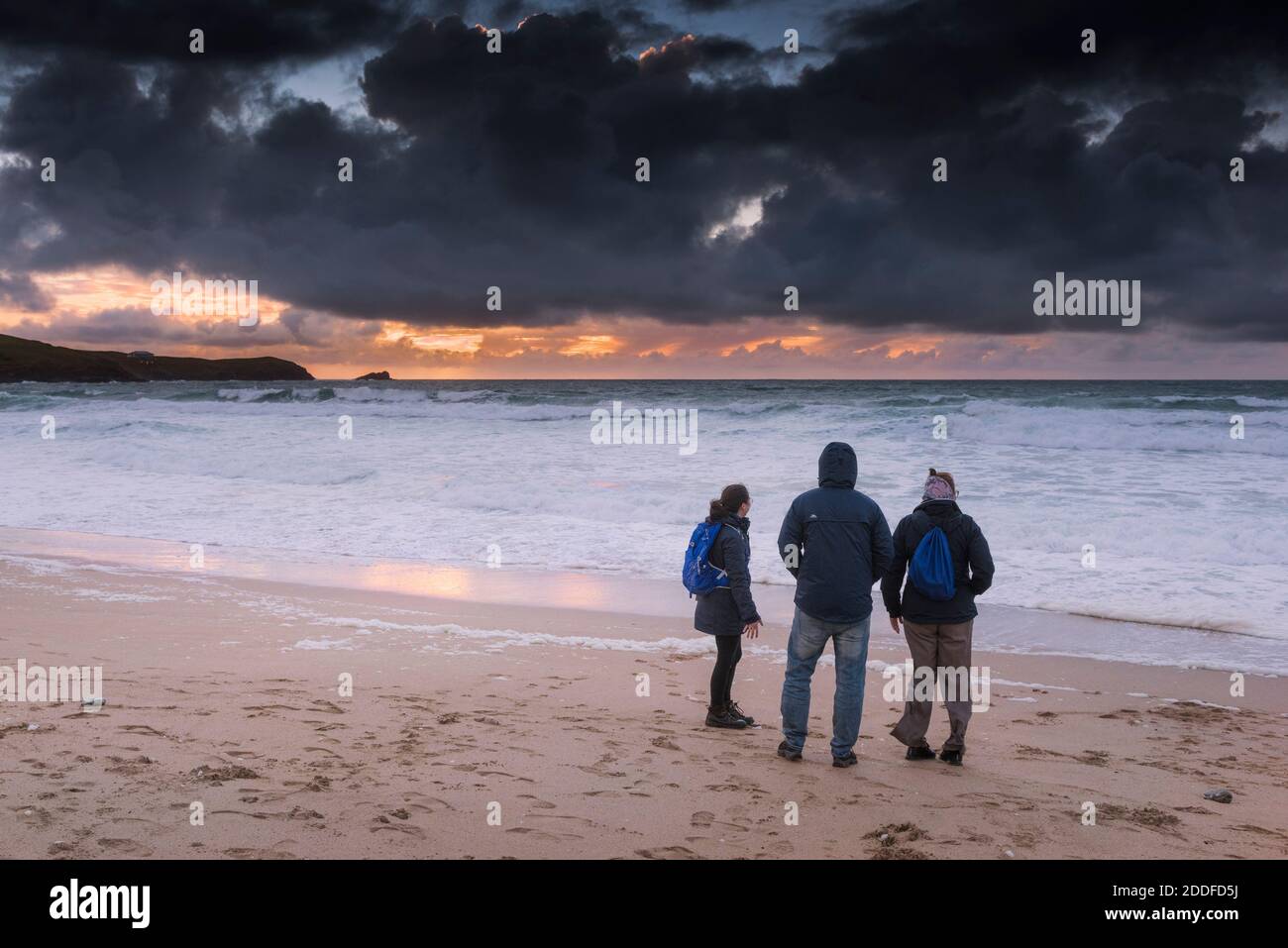 Une famille de vacanciers se tenant sur Fistral Beach et regardant un coucher de soleil spectaculaire à Newquay, dans les Cornouailles. Banque D'Images Une famille de vacanciers se tenant sur Fistral Beach et regardant un coucher de soleil spectaculaire à Newquay, dans les Cornouailles. Banque D'Images