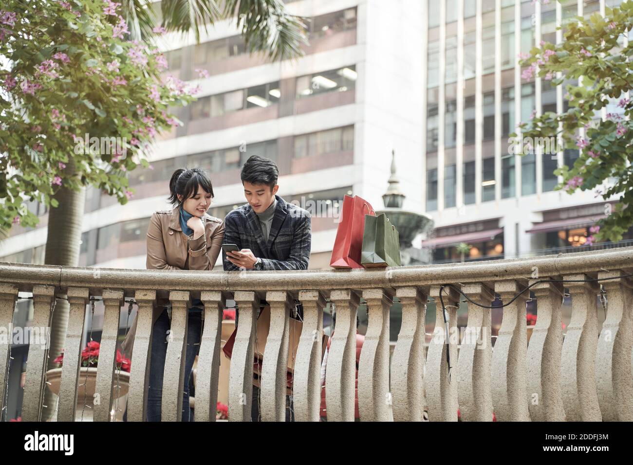 un jeune couple asiatique navigue à l'aide d'un téléphone portable tout en magasiner la ville Banque D'Images