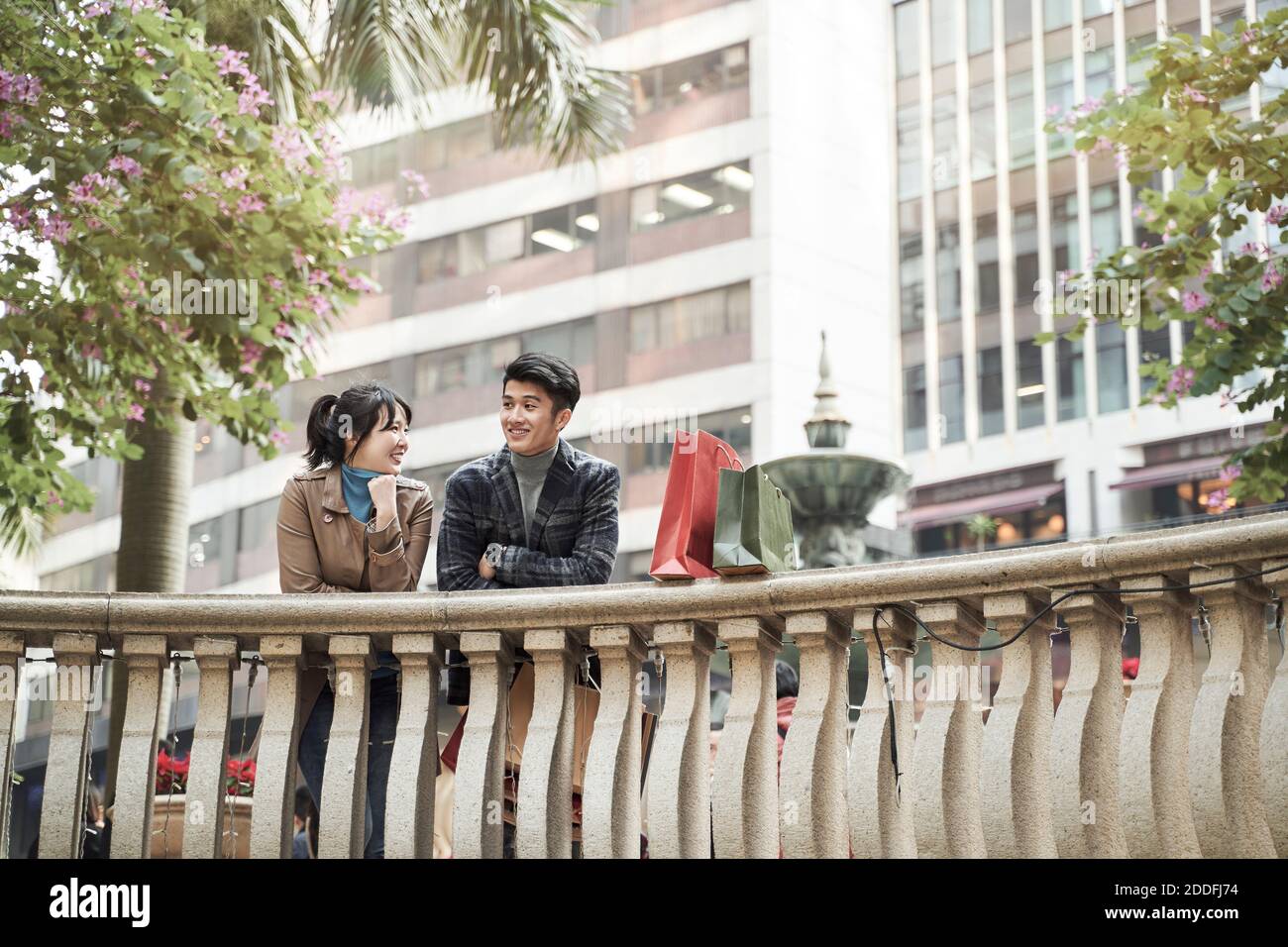 un jeune couple asiatique heureux prend une pause pour discuter en parlant shopping dans la ville Banque D'Images