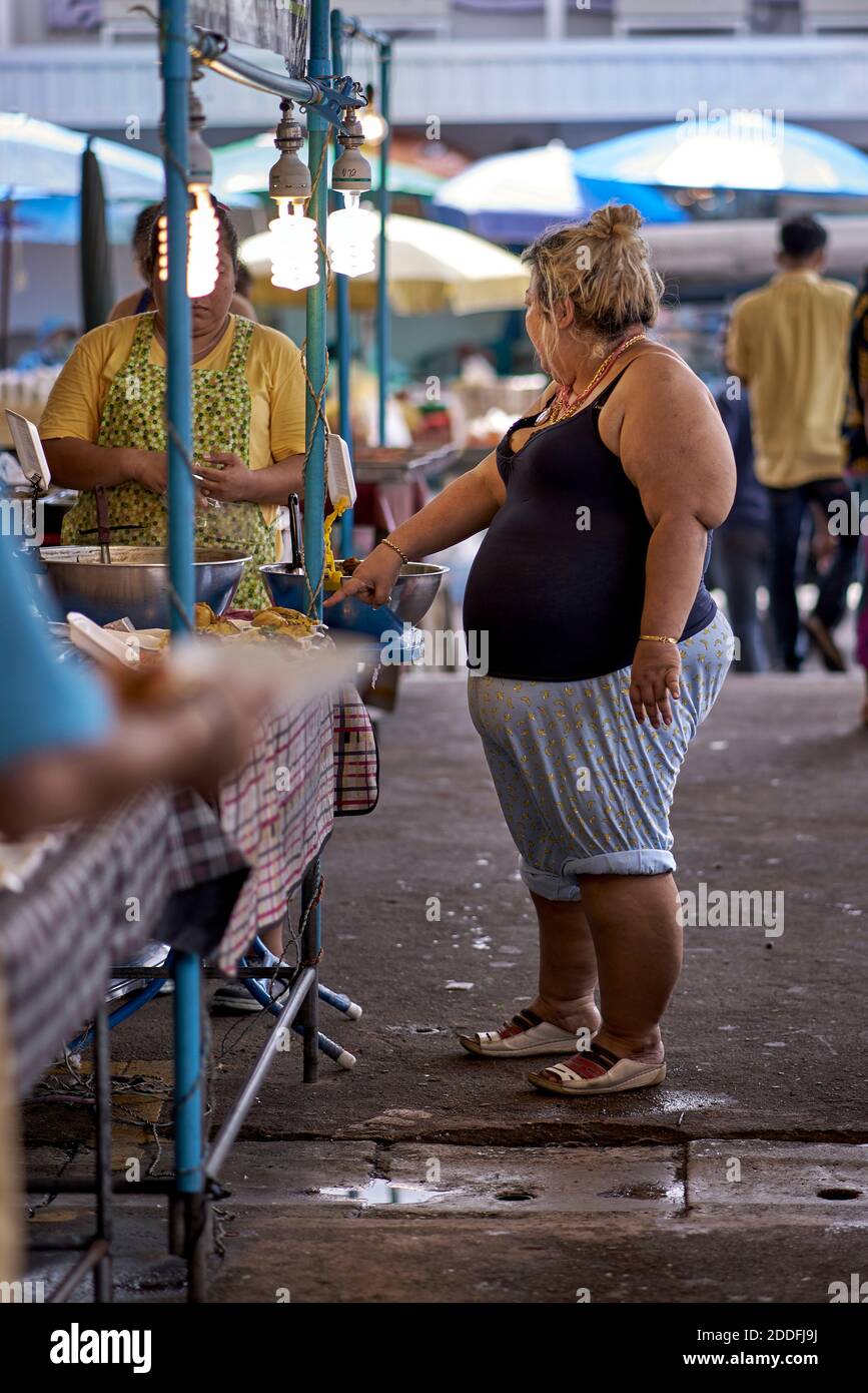 Une femme obèse achète de la nourriture dans un marché thaïlandais Banque D'Images