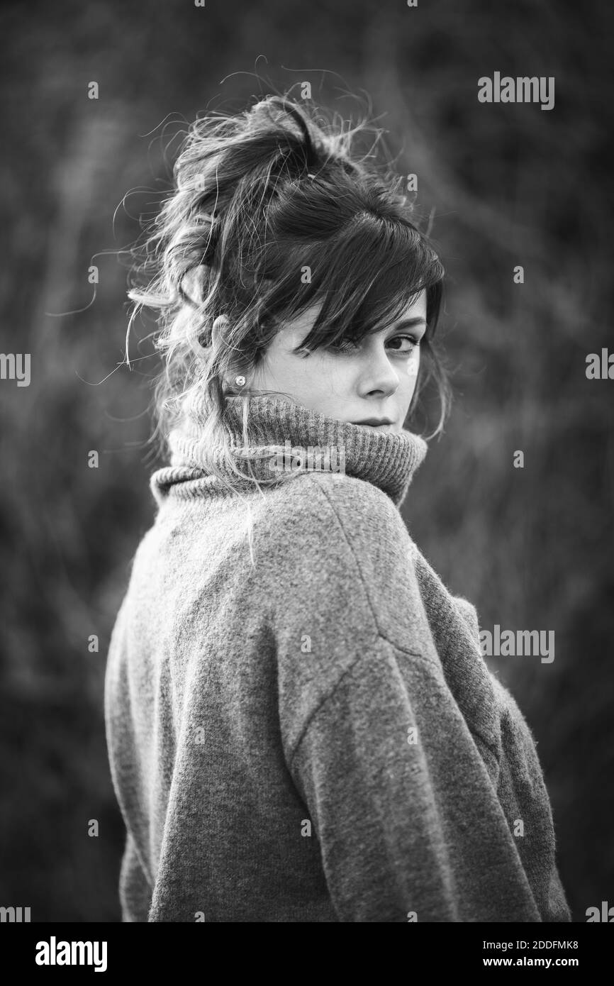 Photo verticale en niveaux de gris d'une jeune femme portant un pull à col roulé gris Banque D'Images
