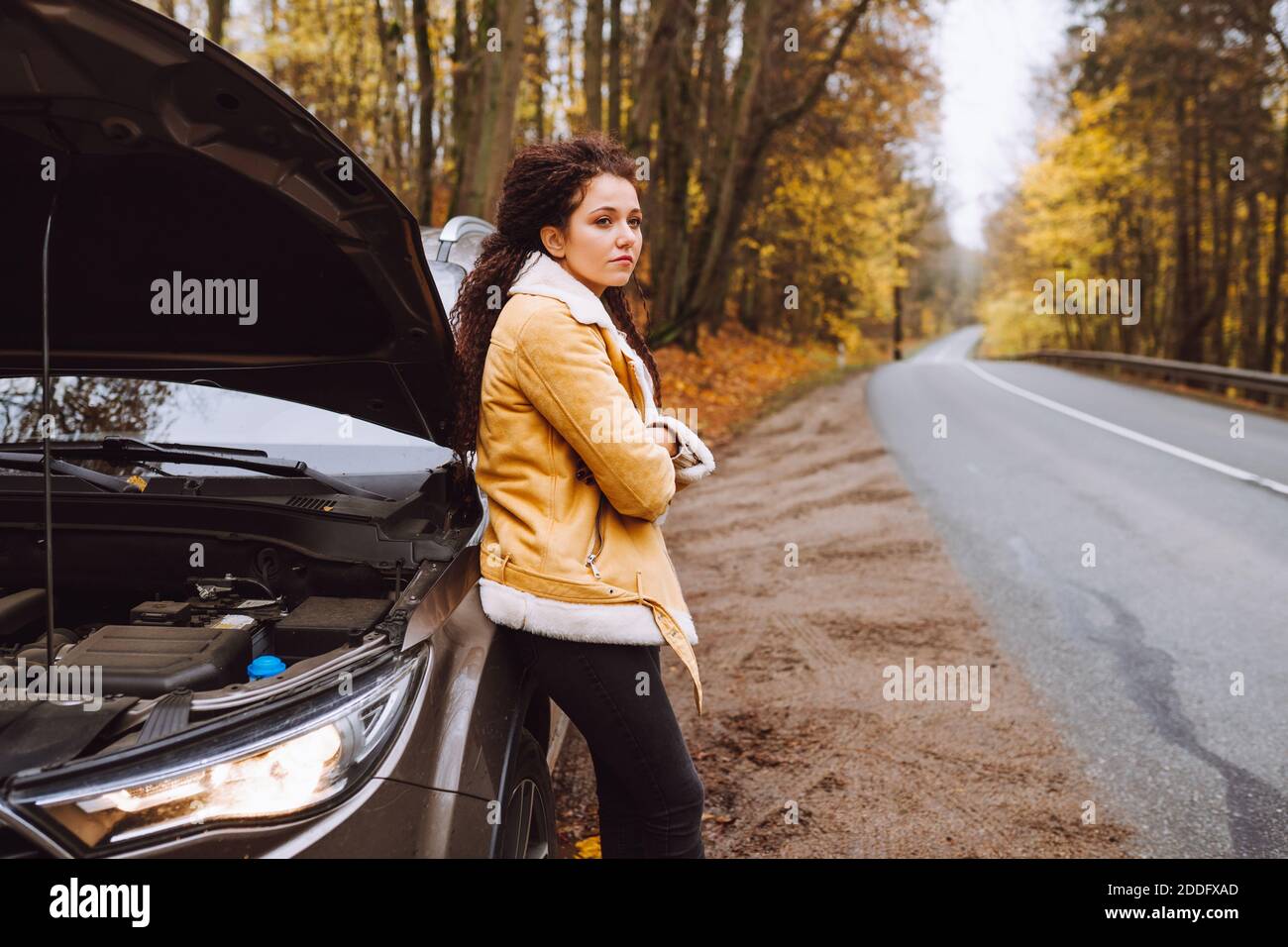 une surprise avo a coiffé une brunette à côté de sa voiture cassée dans la forêt sur route vide Banque D'Images