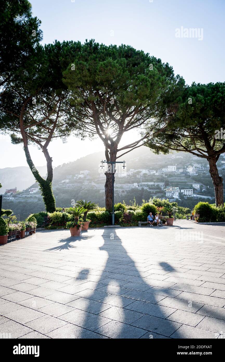 La vue sur la place principale de la ville avec la lumière du soleil venant à travers les grands arbres dans la ville de Ravello, côte amalfitaine, Italie. Banque D'Images