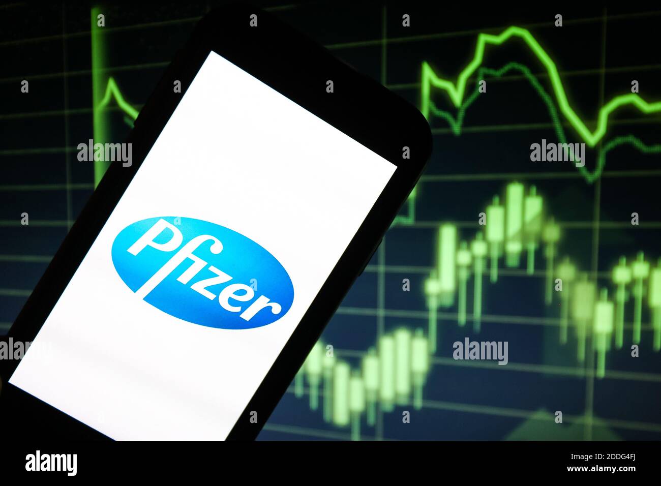 Sur cette photo, le logo de la société pharmaceutique Pfizer est visible affiché sur un smartphone devant un papier vert graphique indiquant la croissance Banque D'Images