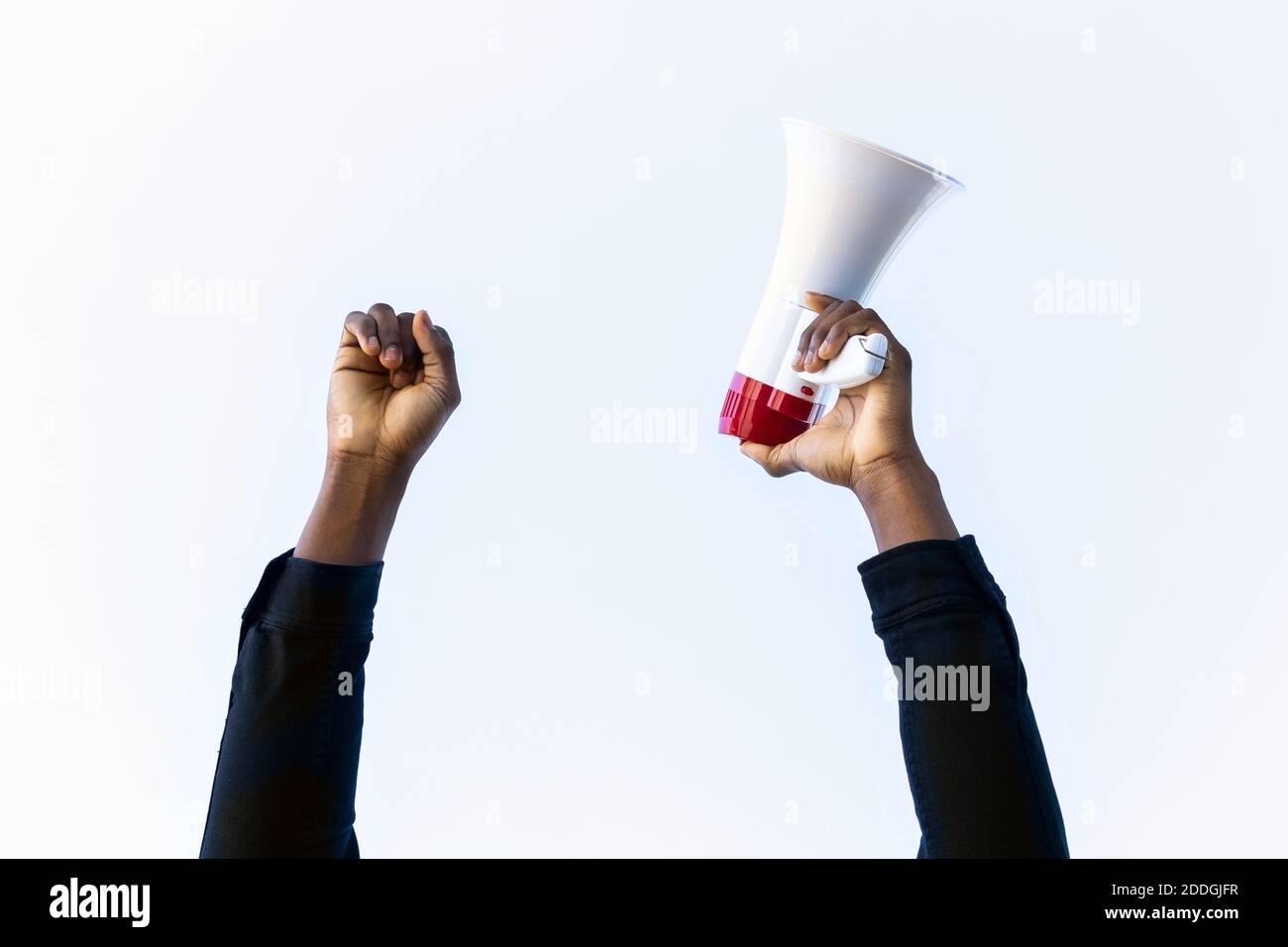 Récolte inreconnaissable de l'Afro-américain avec le mégaphone rouge et blanc debout avec le poing vers le haut sur fond blanc Banque D'Images