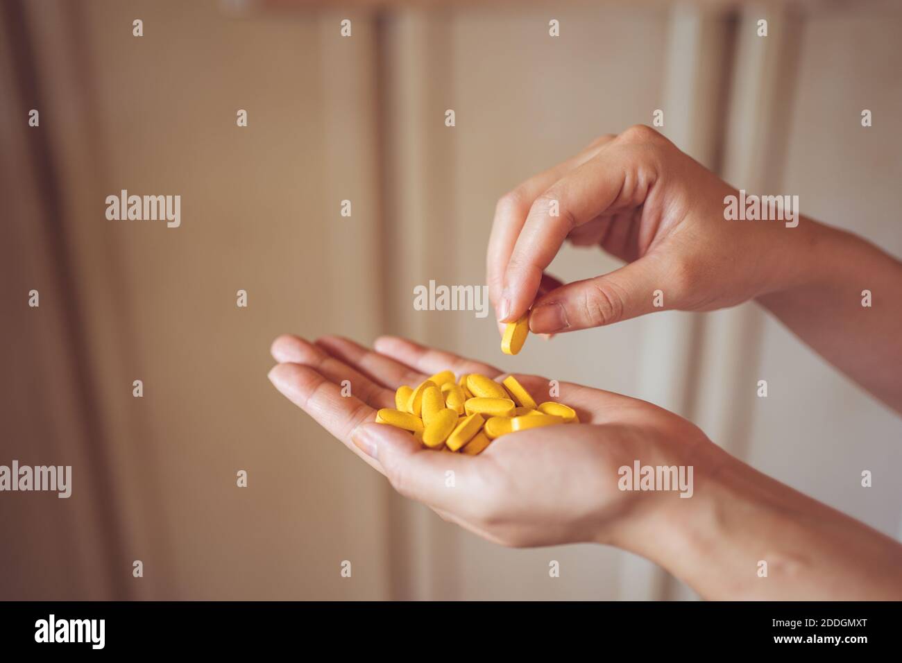 Du dessus de la palmier de récolte de la personne anonyme démontrant la pile des pilules de vitamine jaune pour un mode de vie sain concept Banque D'Images