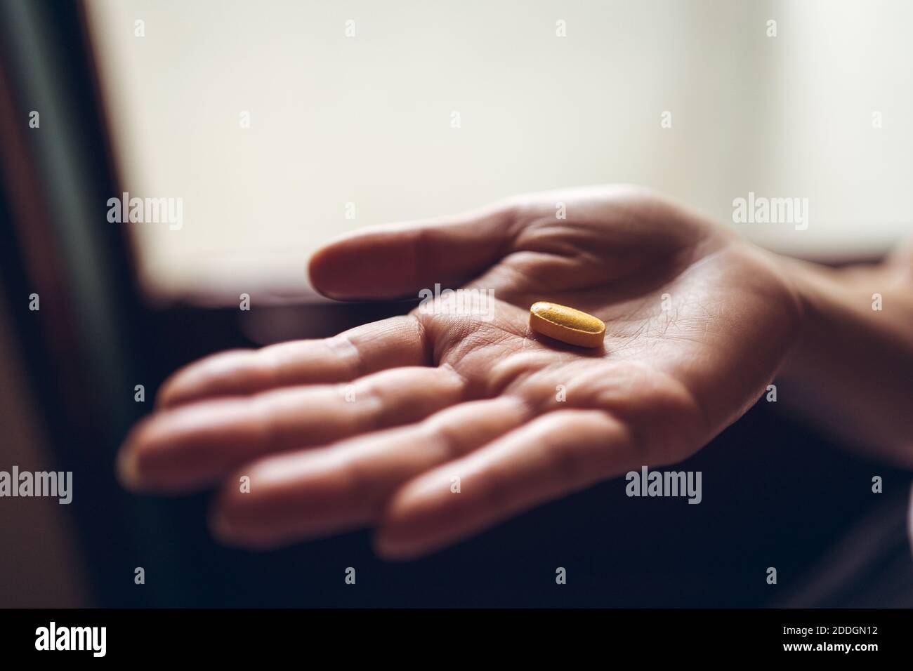 Du dessus de la palmier de récolte de la personne anonyme démontrant le jaune vitamine pilule pour un mode de vie sain concept Banque D'Images