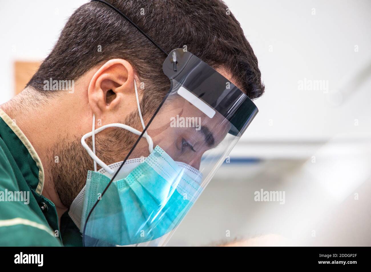 Vue latérale d'un médecin masculin avec masque et visage protéger pendant le travail Banque D'Images