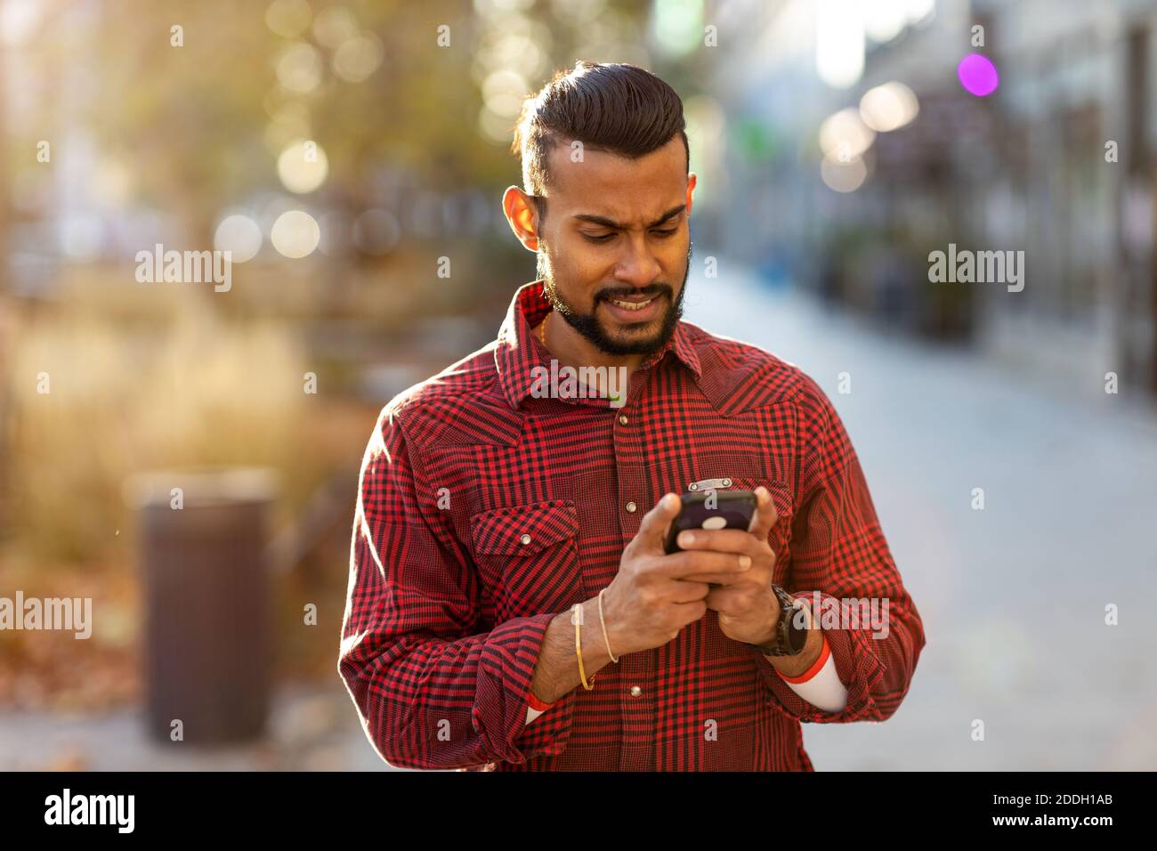 Beau jeune homme utilisant le téléphone portable dans la rue Banque D'Images