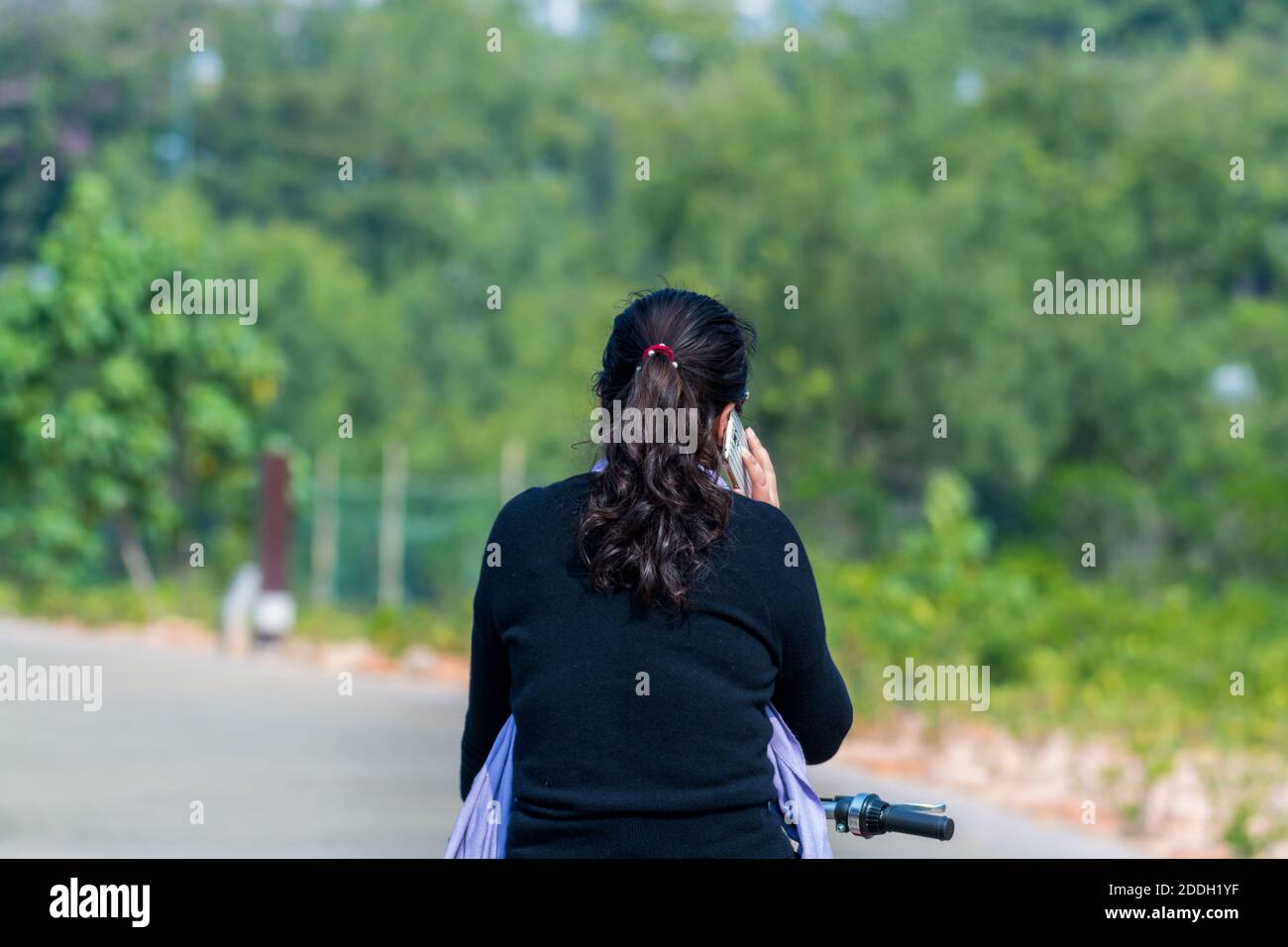 Une chinoise qui fait du vélo et un appel téléphonique à la voie du parc de la baie de Shenzhen, en Chine Banque D'Images