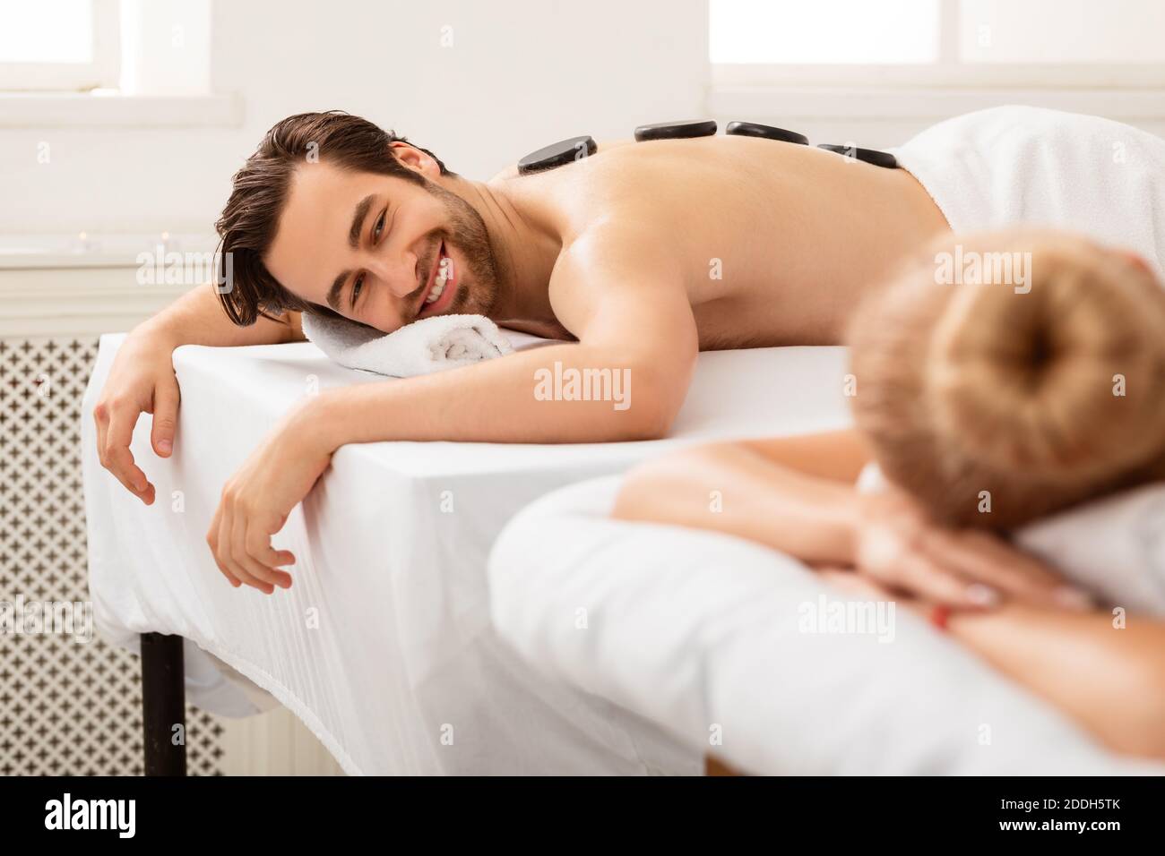 Couple profitant d'un massage de pierre couché et relaxant au salon de spa Banque D'Images