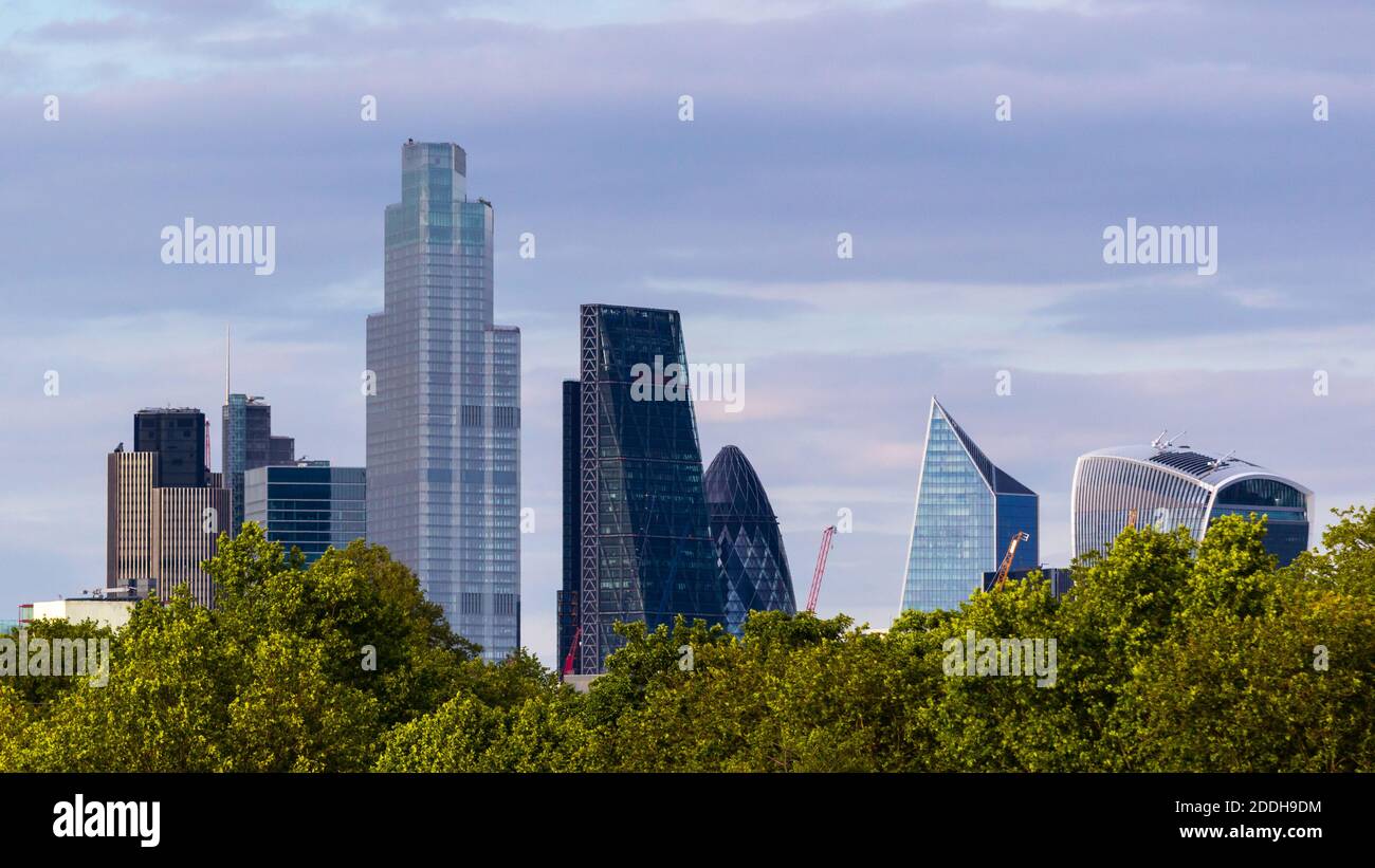 vue lointaine des grands bâtiments de la City de Londres au-delà d'une ligne d'arbres Banque D'Images