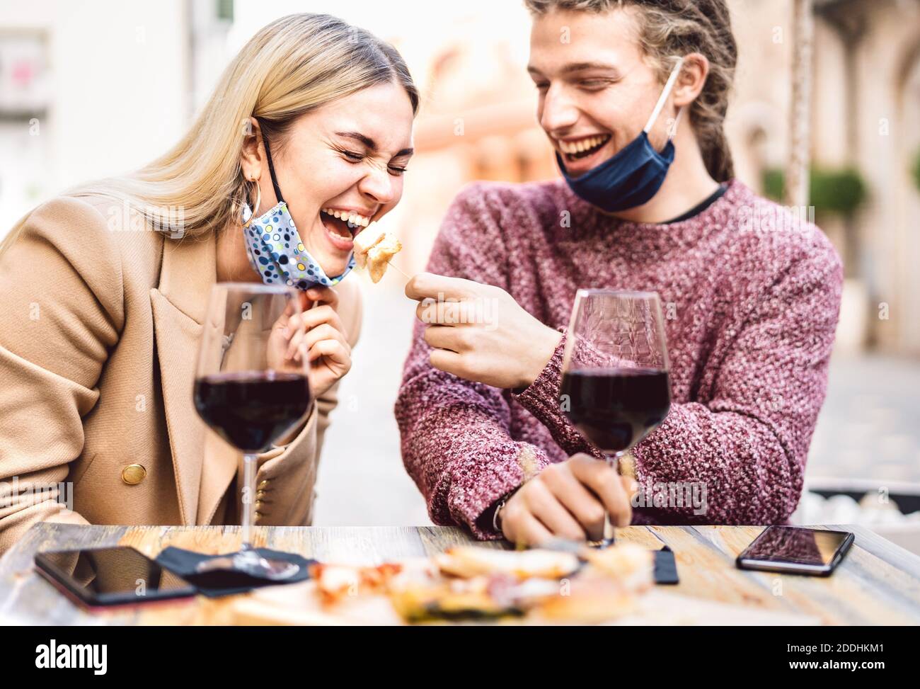 Jeune couple amoureux portant des masques ouverts ayant du plaisir Au bar à vin extérieur - des amis heureux de voyageurs qui apprécient le déjeuner ensemble dans le jardin du restaurant Banque D'Images