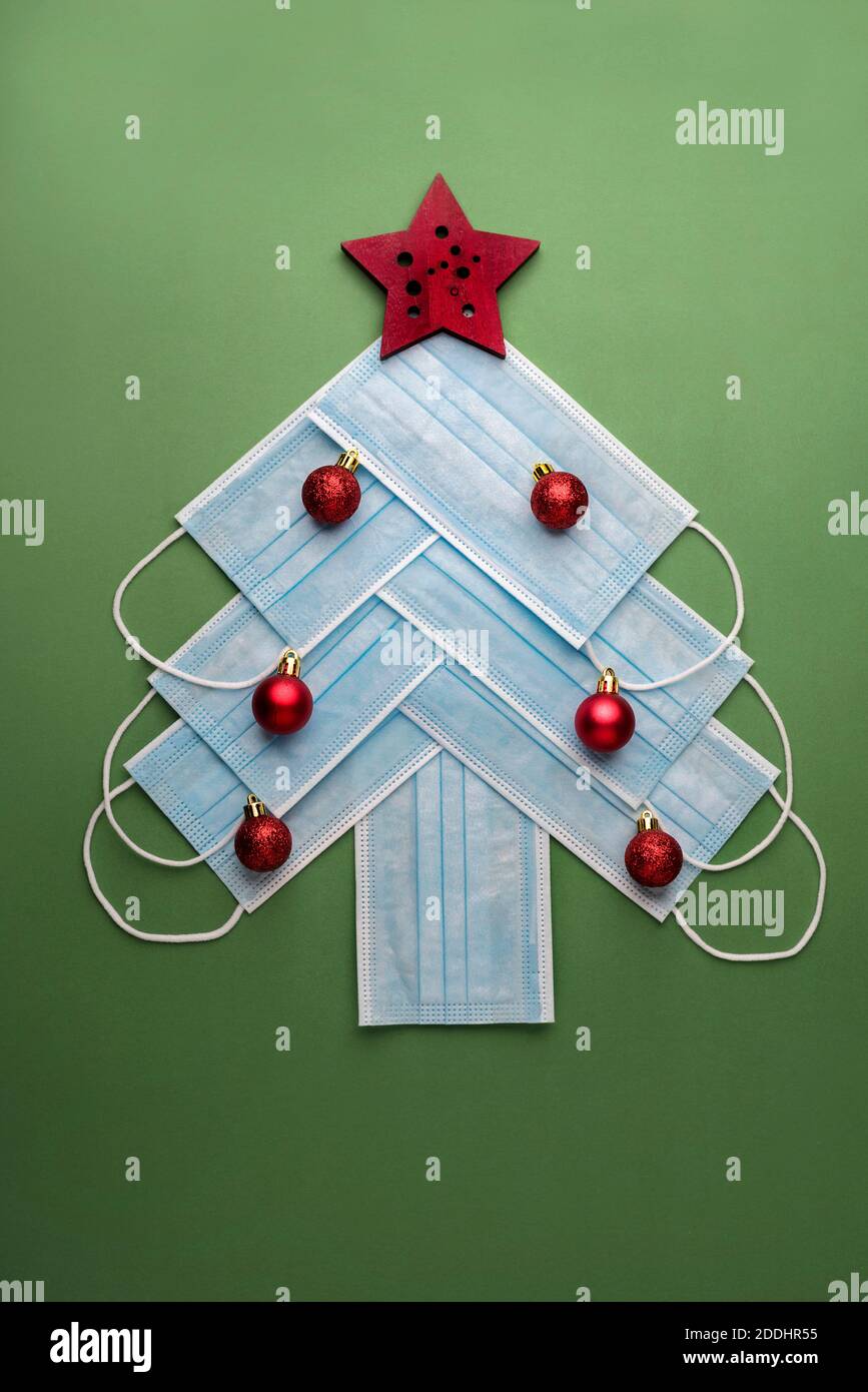 Fond de concept de Noël.masques chirurgicaux protecteurs sous la forme d'un arbre de noël sur fond vert Banque D'Images