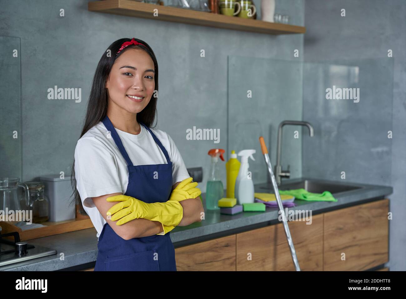 Portrait d'une jolie jeune femme de nettoyage portant des gants de protection, souriant à l'appareil photo, prête pour le nettoyage de la maison. Ménage et entretien ménager, concept de service de nettoyage Banque D'Images