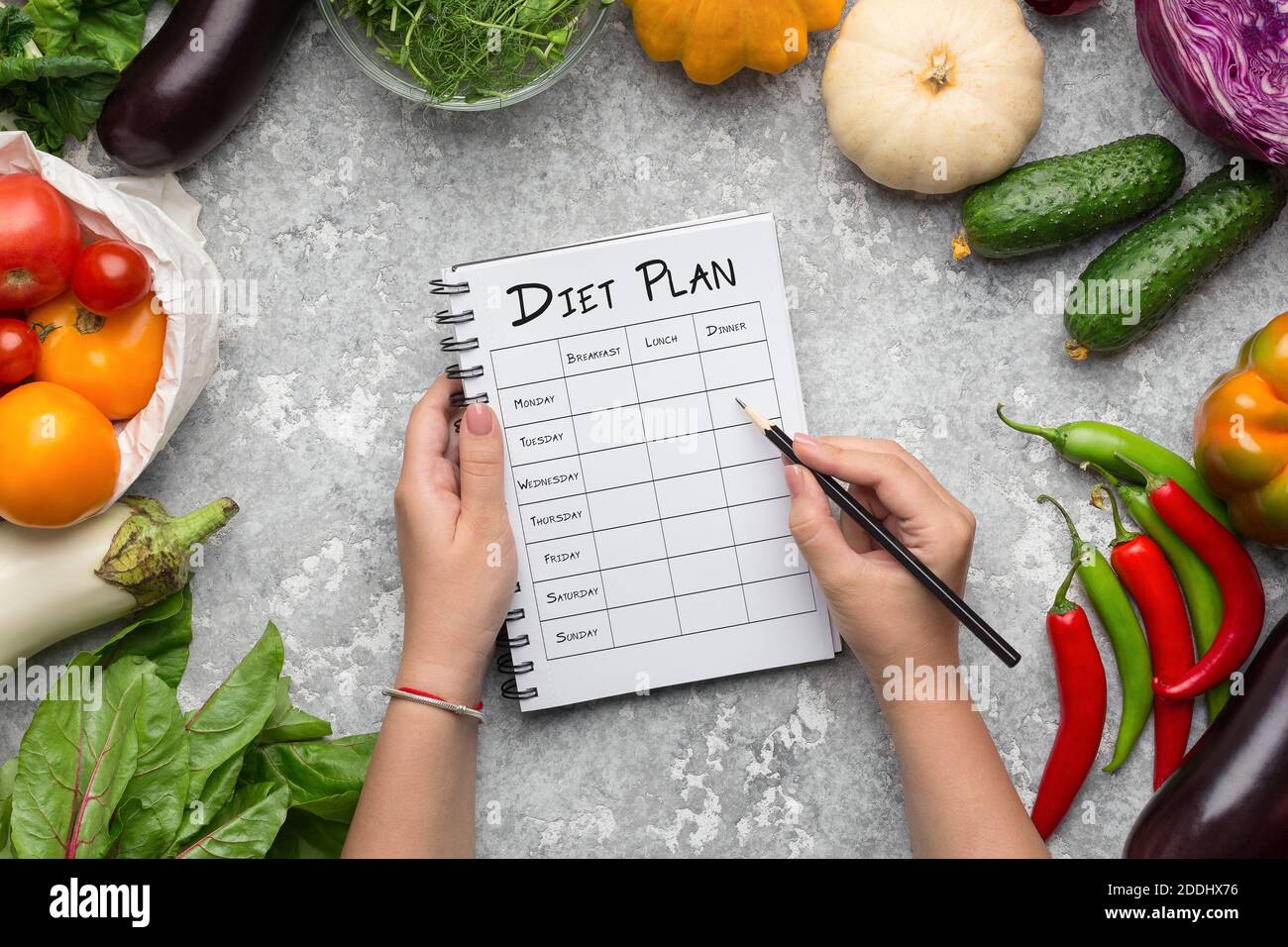 Femme qui remplit le régime alimentaire hebdomadaire à la table avec la composition de Légumes frais Banque D'Images