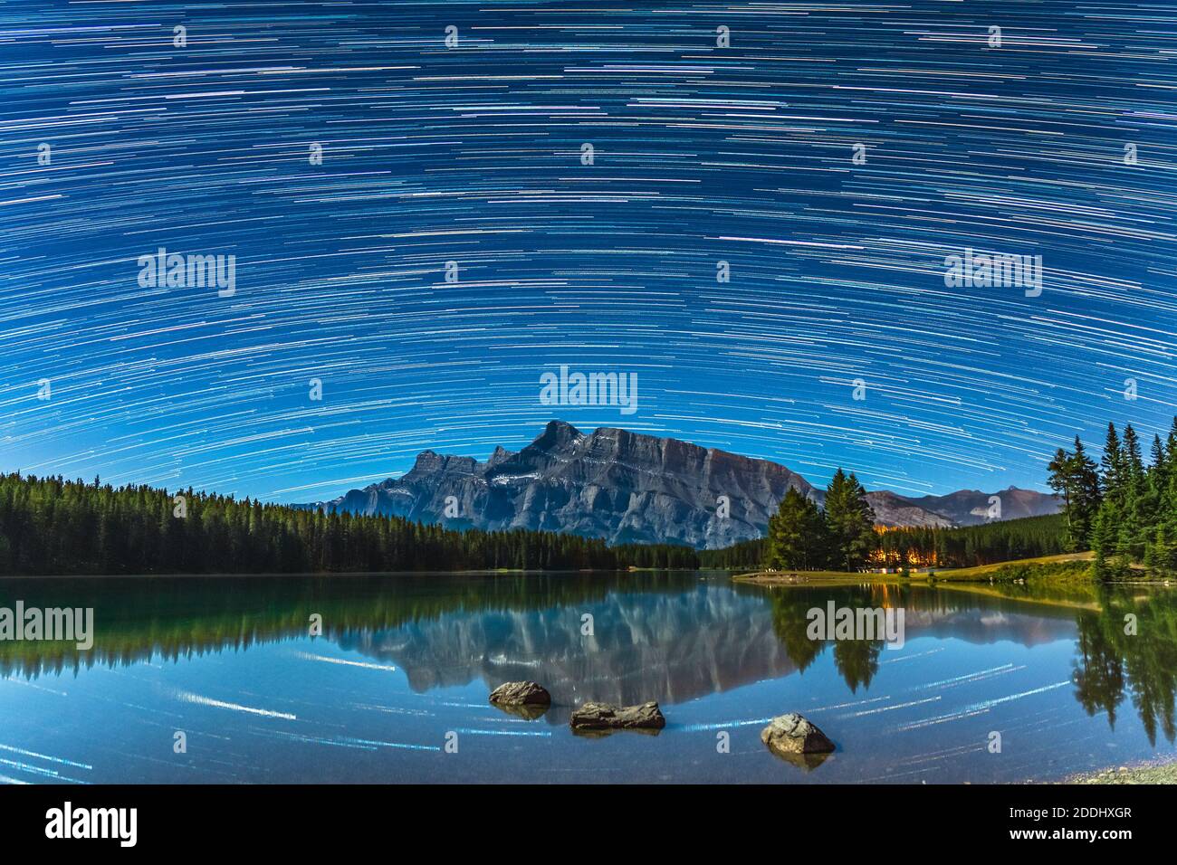 Magnifiques pistes étoiles au-dessus du mont Rundle depuis deux lacs Jack la nuit, ciel étoilé reflété dans la surface de l'eau. Paysage dans le parc national Banff Banque D'Images