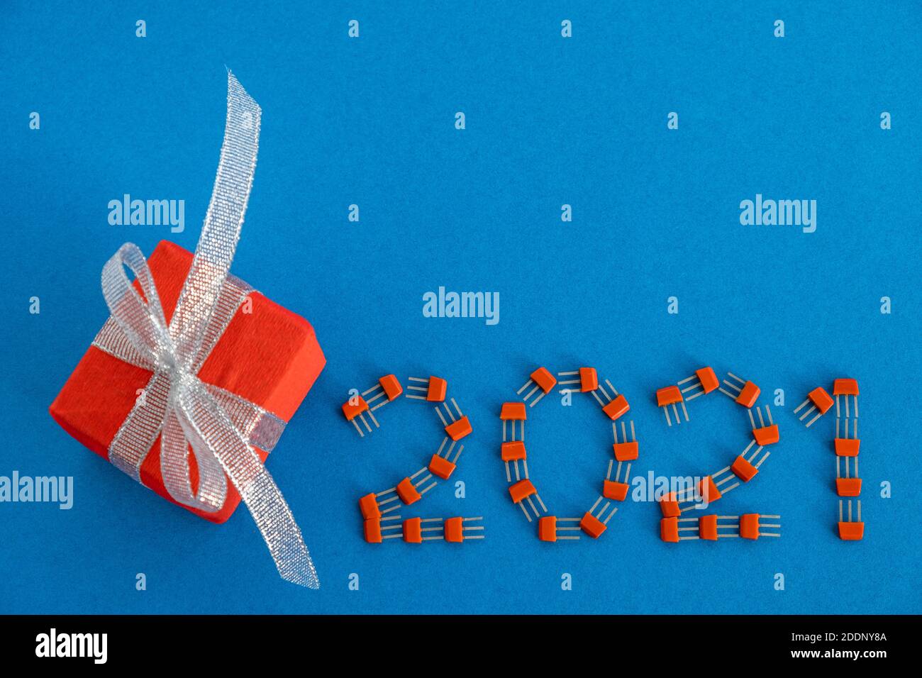 Carte de Noël créative. 2021 de transistors sur fond bleu avec un cadeau dans un boîtier rouge. Concept créatif de la nouvelle année. Copier l'espace. Banque D'Images