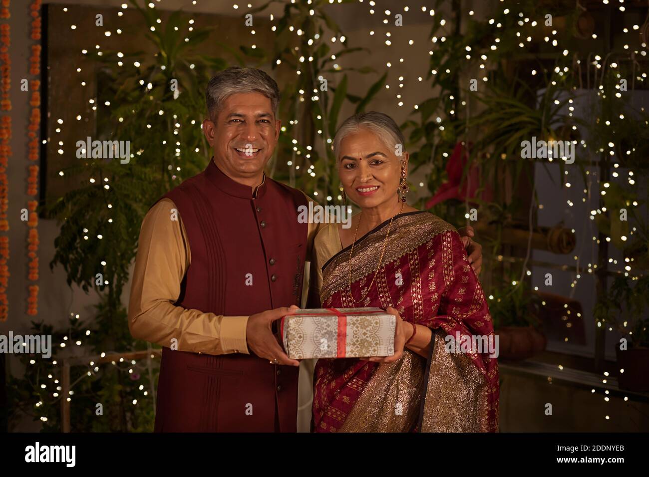 Un portrait d'un couple senior REGARDANT L'APPAREIL PHOTO ET ÉCHANGER DES CADEAUX DIWALI Banque D'Images