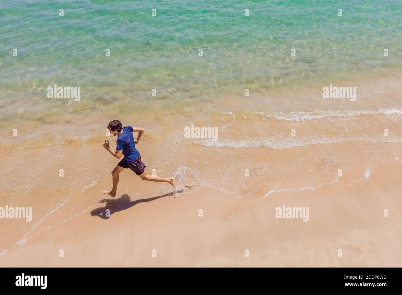 Coureur courant sur la plage au bord de l'océan - vue d'en haut. Homme athlète entraînement cardio jogging faire l'entraînement du matin. Vue de drone aérienne de héros, beaucoup Banque D'Images