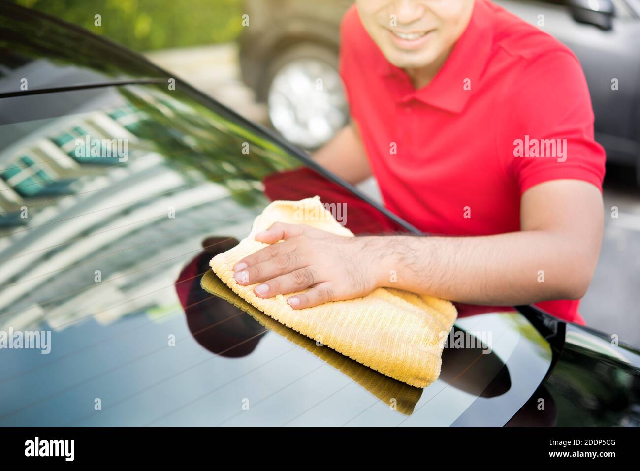 Le personnel du service automobile nettoie le pare-brise arrière de la voiture avec un chiffon en microfibre - détail de voiture et concept de valeting Banque D'Images