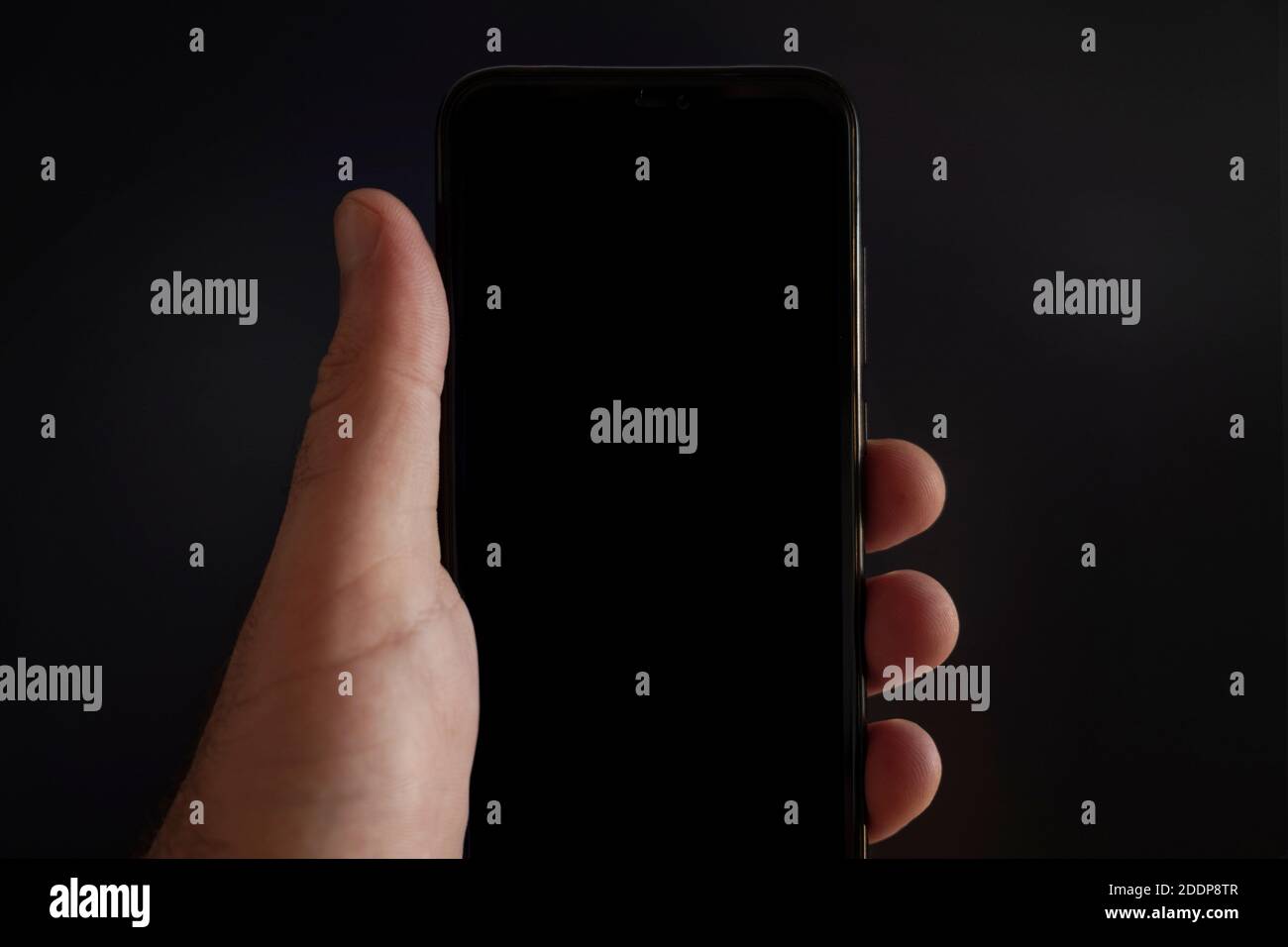 Vue rapprochée de l'écran noir d'un smartphone enfermé par une main sur fond noir. Placez votre texte ici Banque D'Images