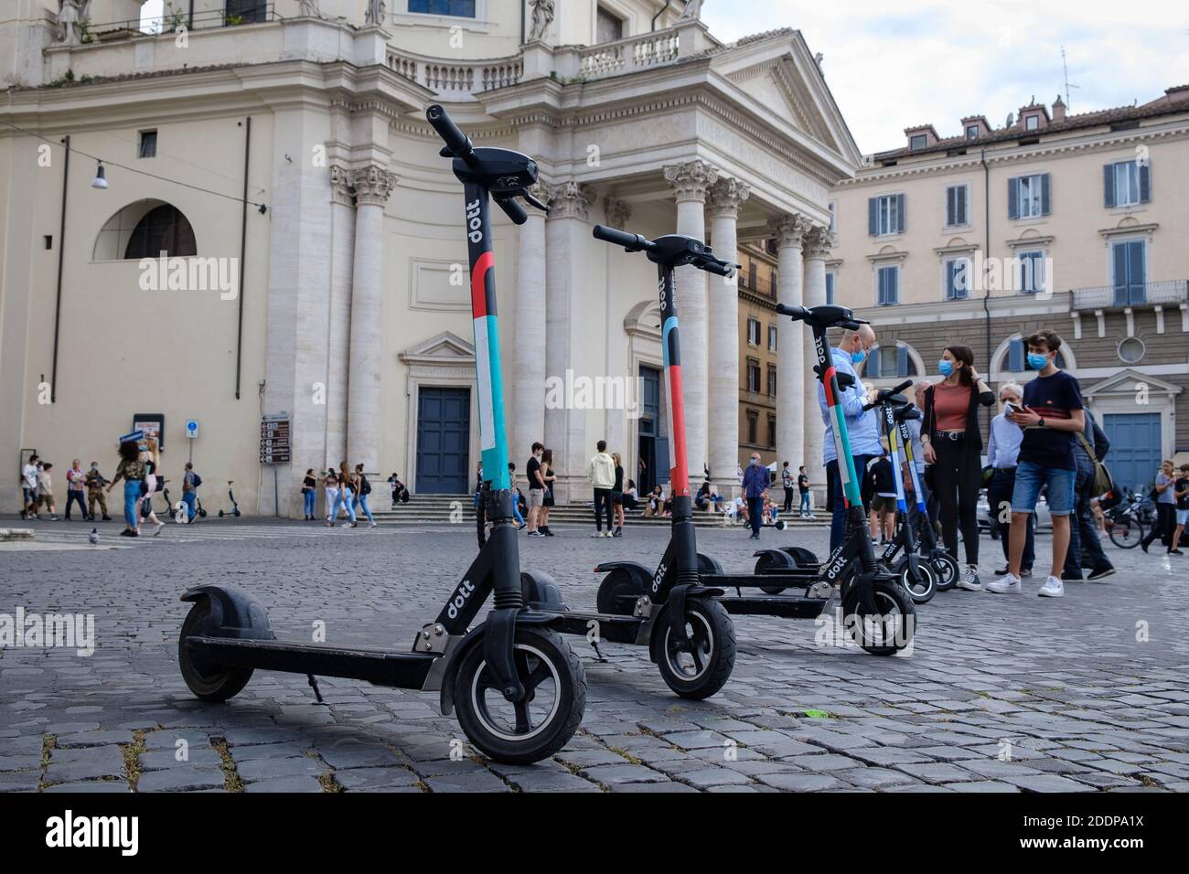 Scooters électriques Dott garés sur la Piazza del Popolo alignés et prêts à louer. En arrière-plan, certains gars les louent en utilisant l'application RideDott pour Banque D'Images