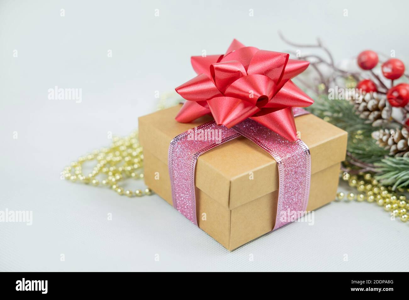 boîte cadeau surprise ornée d'un noeud rose et d'un décor Sur le fond d'une branche d'arbre de Noël pour le Nouvel an et Saint-Valentin Banque D'Images